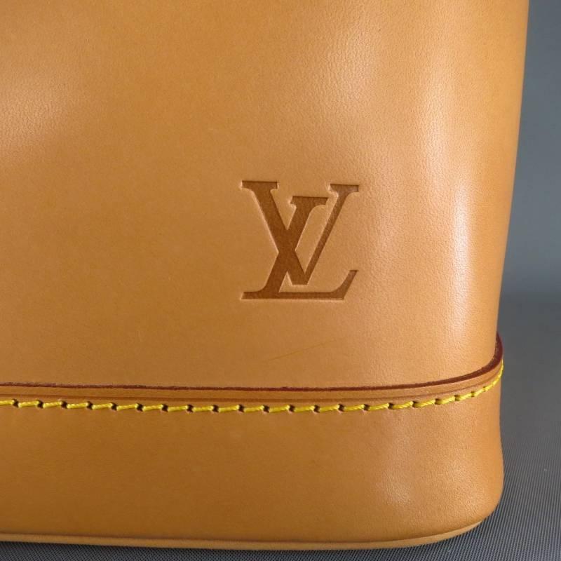 This ultra rare limited edition ALMA PM by LOUIS VUITTON comes in all natural Vacchetta patina leather and features a structured taper shape with rectangular base, double top handles with gold tone hardware, zip closure with LV lock and keys, and