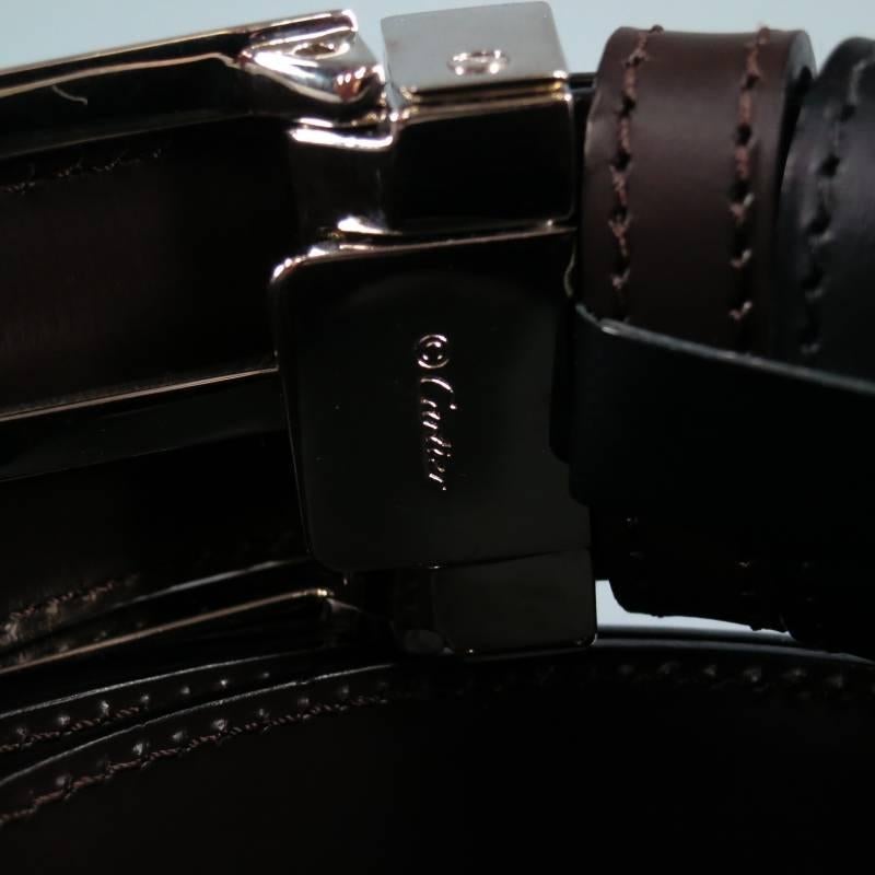 Classic dual tone dress belt by CARTIER. A two tone style with dual color options, this piece comes in smooth black and deep chocolate brown leather and features a detachable silver tone embossed buckle. Made in France.
Retails: $560.00

New