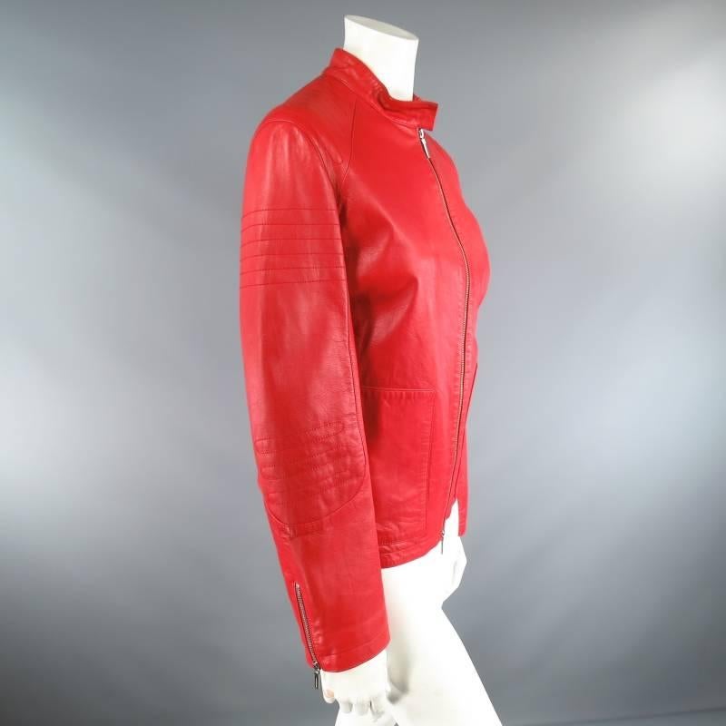 This ultra chic motorcycle jacket by JIL SANDER comes in a vibrant red soft leather and features a stand up collar that snaps over to one side, embroidered moto shoulder details, silver tone double zip closure, frontal zip pockets, and long zip
