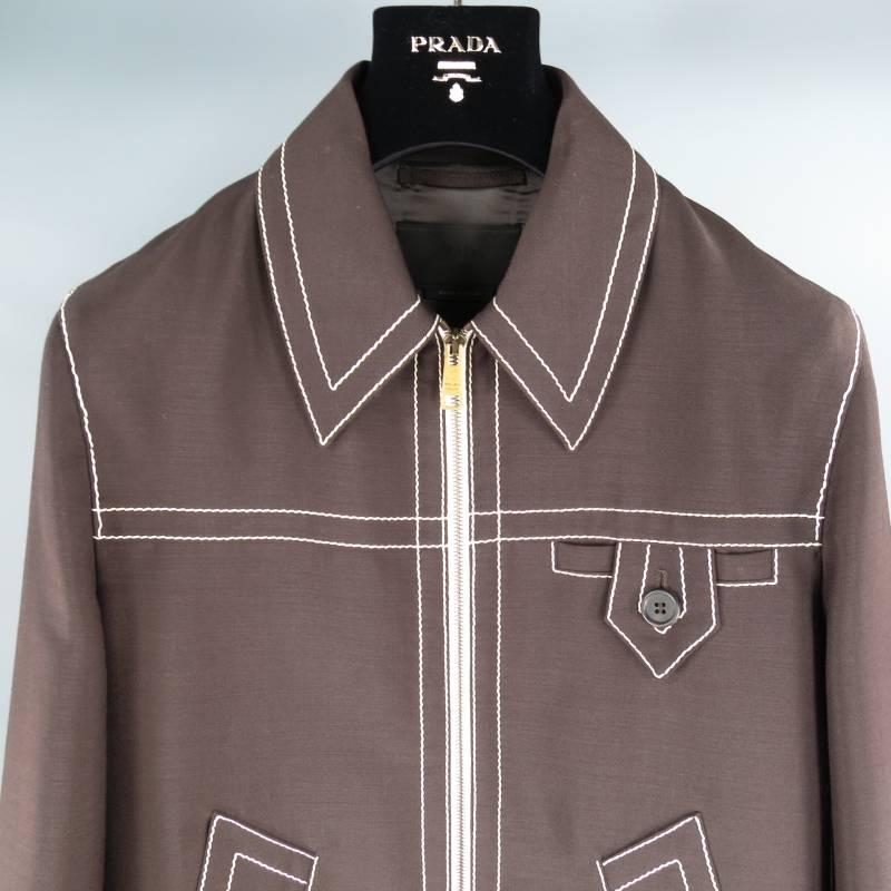 Prada Jacket consists of mohair/wool material in a brown color tone. Designed in a cropped fit, pointed spread collar with contrast white stitching that can be seen throughout body. Brass zipper opening with white trim, single button cuff on each