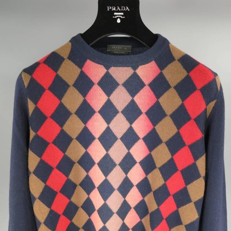 Prada Pullover consists of wool material in a multi-color navy tone. Designed with a crew-neck collar, ribbed cuffs and blousen hem. Detailed with an argyle pattern front in multi-color (red, brown, coral) and sold navy sleeves and back. Made in