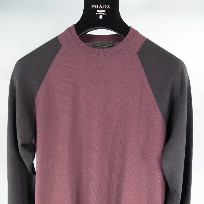 Prada Pullover consists of merino wool material in a eggplant and black color tone. Designed with a raglan chest pattern, color blocked appearance with black sleeves, charcoal cuffs and eggplant body. Crew-neck detail, ribbed cuffs, light weight