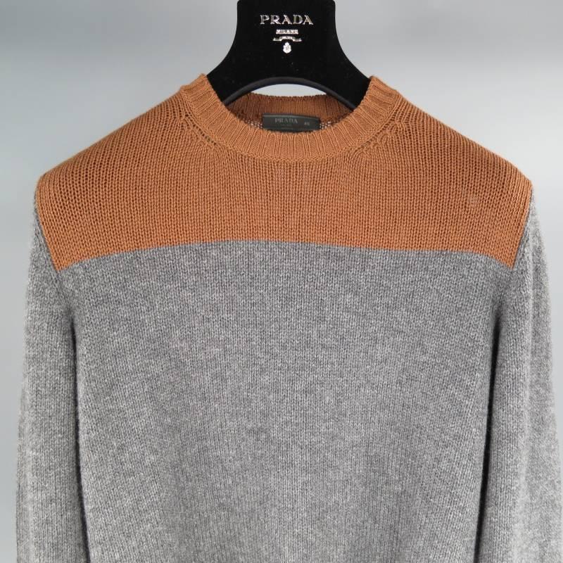 Prada Sweater consists of wool material in a grey and copper color tone. Designed with a crew-neck collar, 2 tone color blocked pattern with shoulder/chest section in copper and body in grey. Ribbed detail can be seen on cuff and collar. Made in