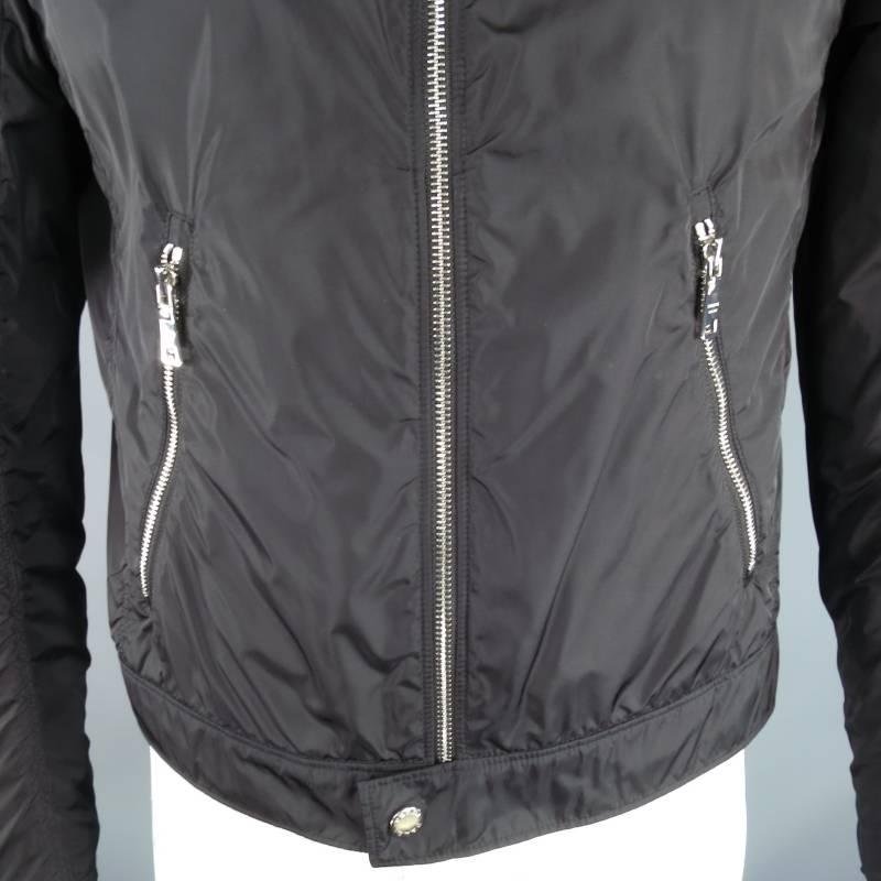 This light weight PRADA jacket comes in a nylon windbreaker fabric and features a classic motorcycle jacket cut, band collar with silver tone logo snap tab, silver tone zip closure, waistband with snap tab, symmetrical zip slit pockets, and zip