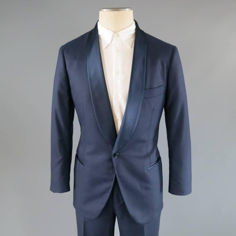 Brunello Cucinelli Tuxedo consists of a wool blend material in a rich navy color tone. Designed with a shawl lapel collar in a silk material, single button front and tone-on-tone stitching seen along mid-section. Detailed with a top pocket square