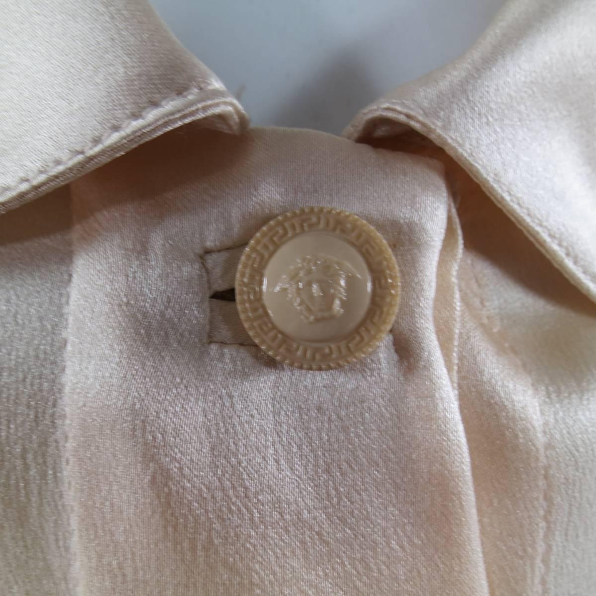 This gorgeous GIANNI VERSACE blouse comes in a light peachy nude silk satin and features a curved collar with matching Medusa button, hidden placket buttopn closure and French cuffs. Made in Italy.
 
Excellent Pre-Owned Condition.
Marked: 38
