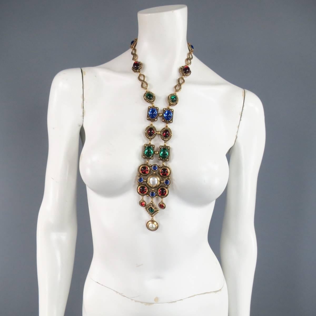 This stunning OSCAR DE LA RENTA historical European / Egyptian inspired statement necklace comes in gold tone engraved and rhinestone studded metal and features a long center piece with gorgeous ruby red, green, and blue jewels and faux pearls in a
