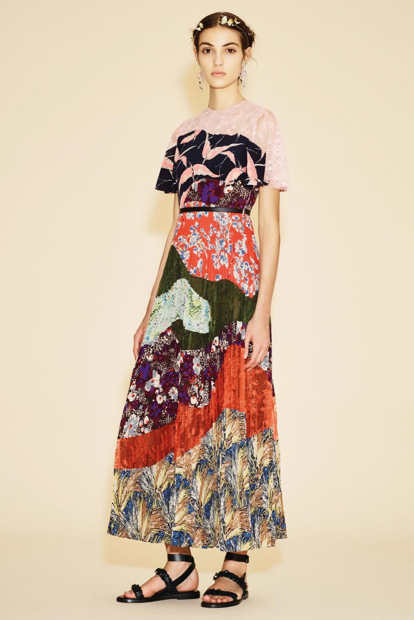 Valentino cocktail dress features a navy and pink bird print fabric and lace top with ruffled sleeves, black leather applique belt, and mixed floral print fabric and lace curved patchwork accordion pleated maxi skirt. Minor disturbances throughout