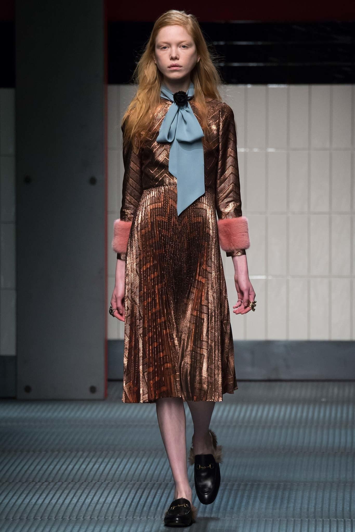 GUCCI cocktail dress comes in metallic rose gold zig zag print lurex fabric and features a light blue tied collar, three quarter sleeves with pink mink cuffs, and accordion pleated A line skirt. Minor disturbances in pleats on back. As-is. Made in