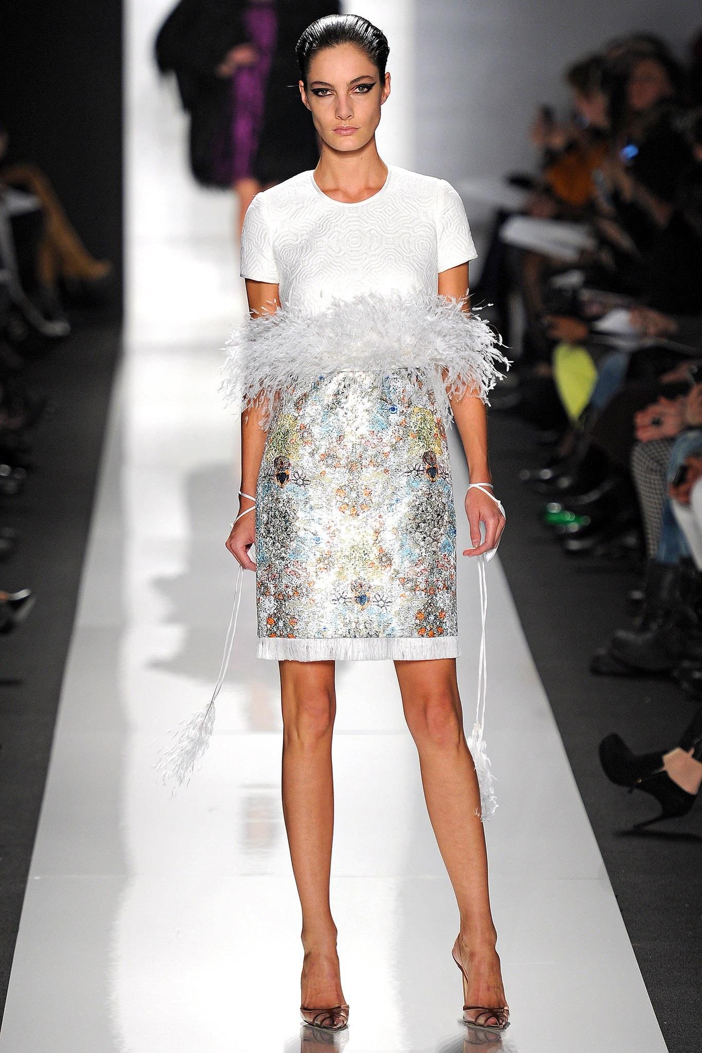 Ralph Rucci  cocktail dress features a quilted cream short sleeve top with chiffon crewneck and button up back, dramatic white feather belt panel, and sequin printed pencil skirt with fringe hem. Made in USA.  Fall 2013.  Retail Price: $10,000
 
New