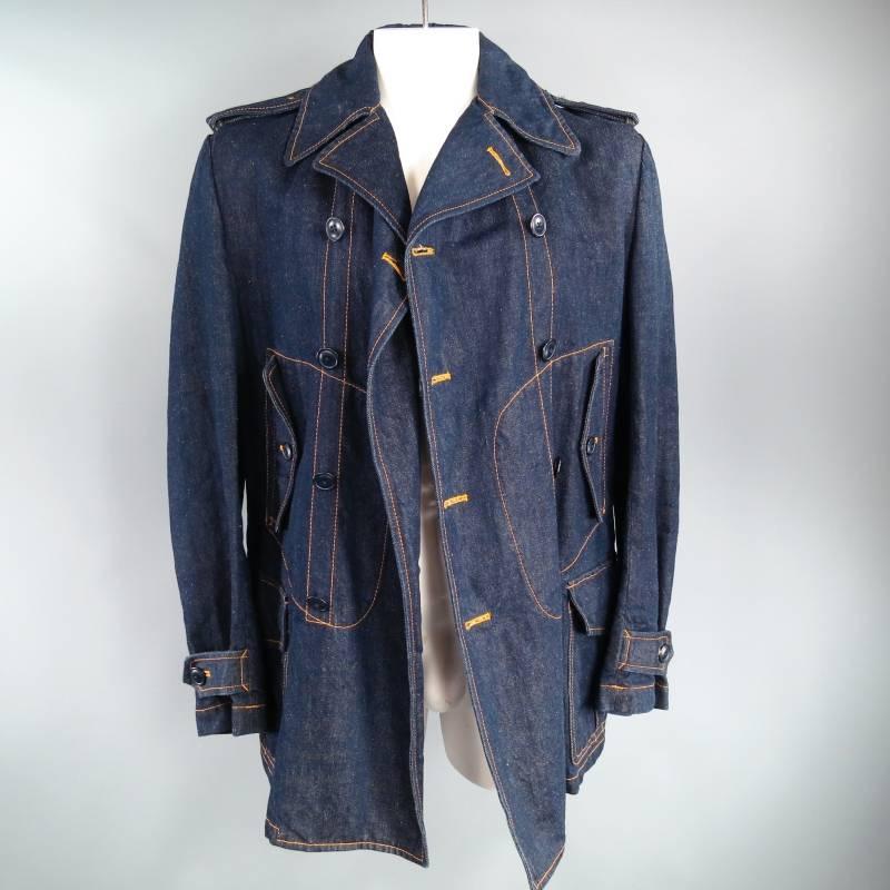 JUNYA WATANABE Coat consists of denim material in a blue indigo color tone. Designed with a Double Breasted front, contrast stitching seen throughout edge and body of coat, black buttons with multi-front button closure pockets. Notch lapel collar