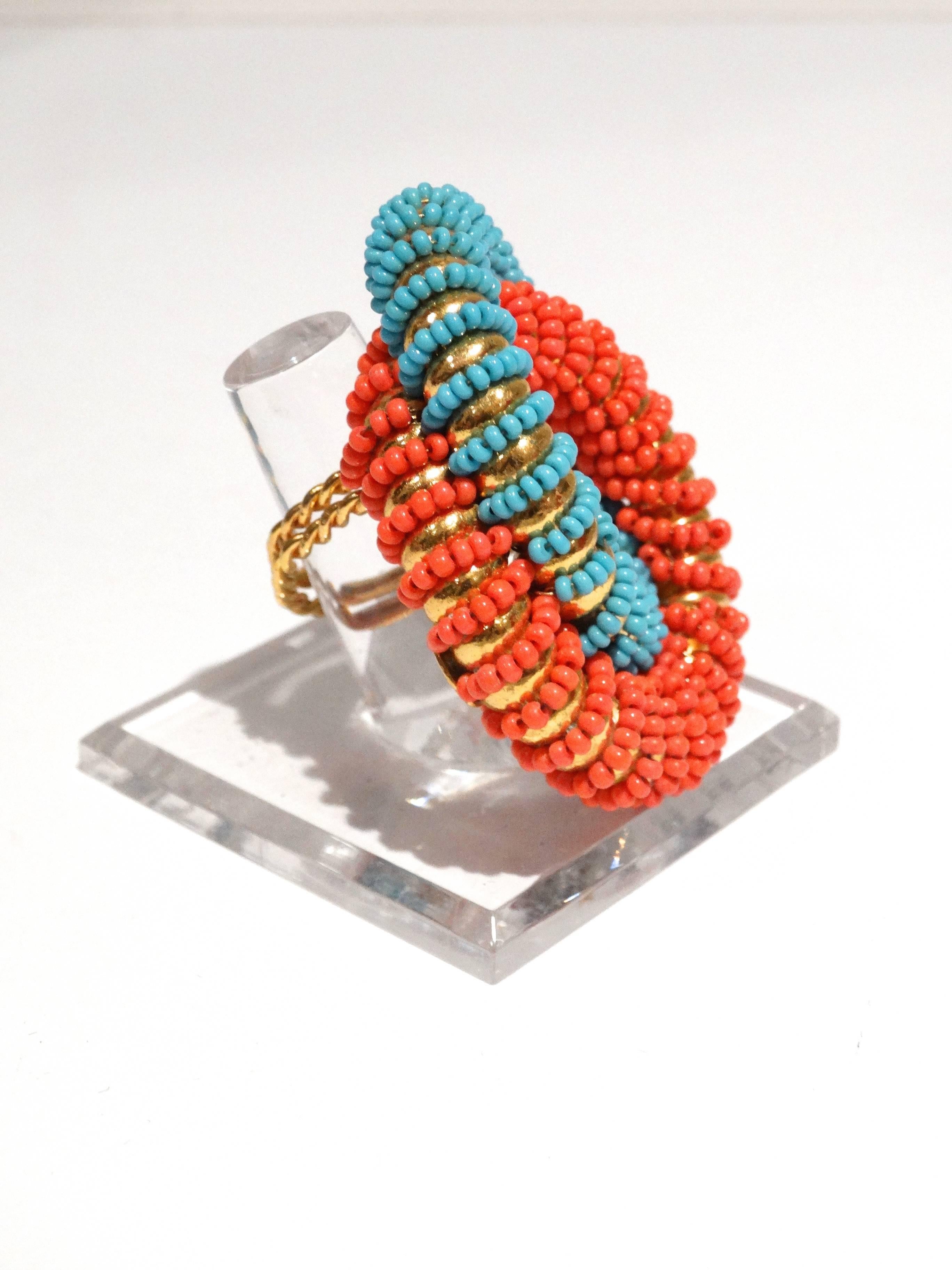This fabulous ring designed by William De Lillo is with two-connected circles. The circles feature faux beads in coral and turquoise colors that spiral around each circle. Great color combo, in turquoise and coral. This ring is a unique double