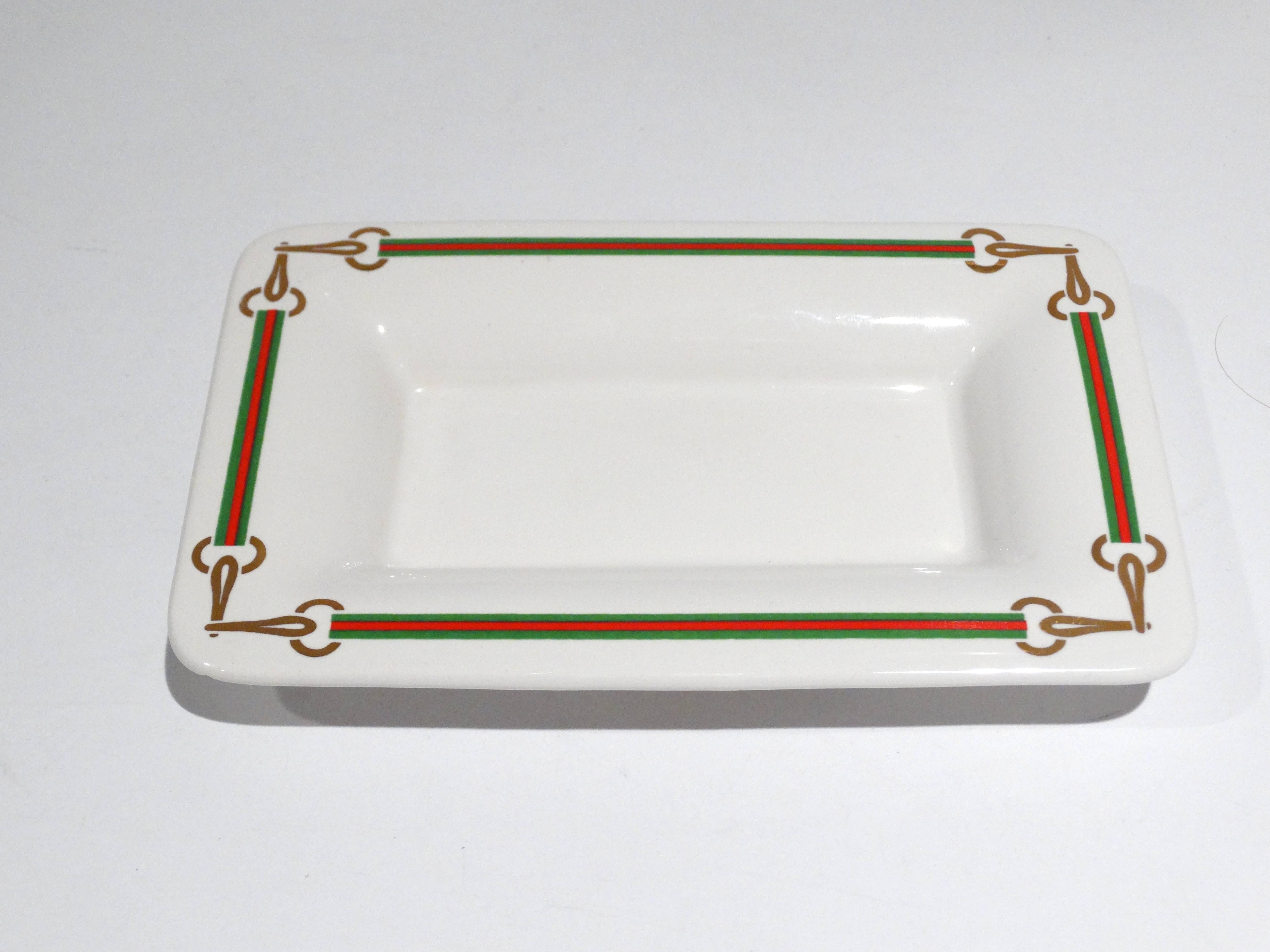 Vintage Gucci horsebit ashtray or trinket dish. This dish is contoured with signature red and green colors and interlocking gold color Horsebits. There is a tiny chip on one of the corners, it is unnoticeable. This piece is stamped Made in Italy by