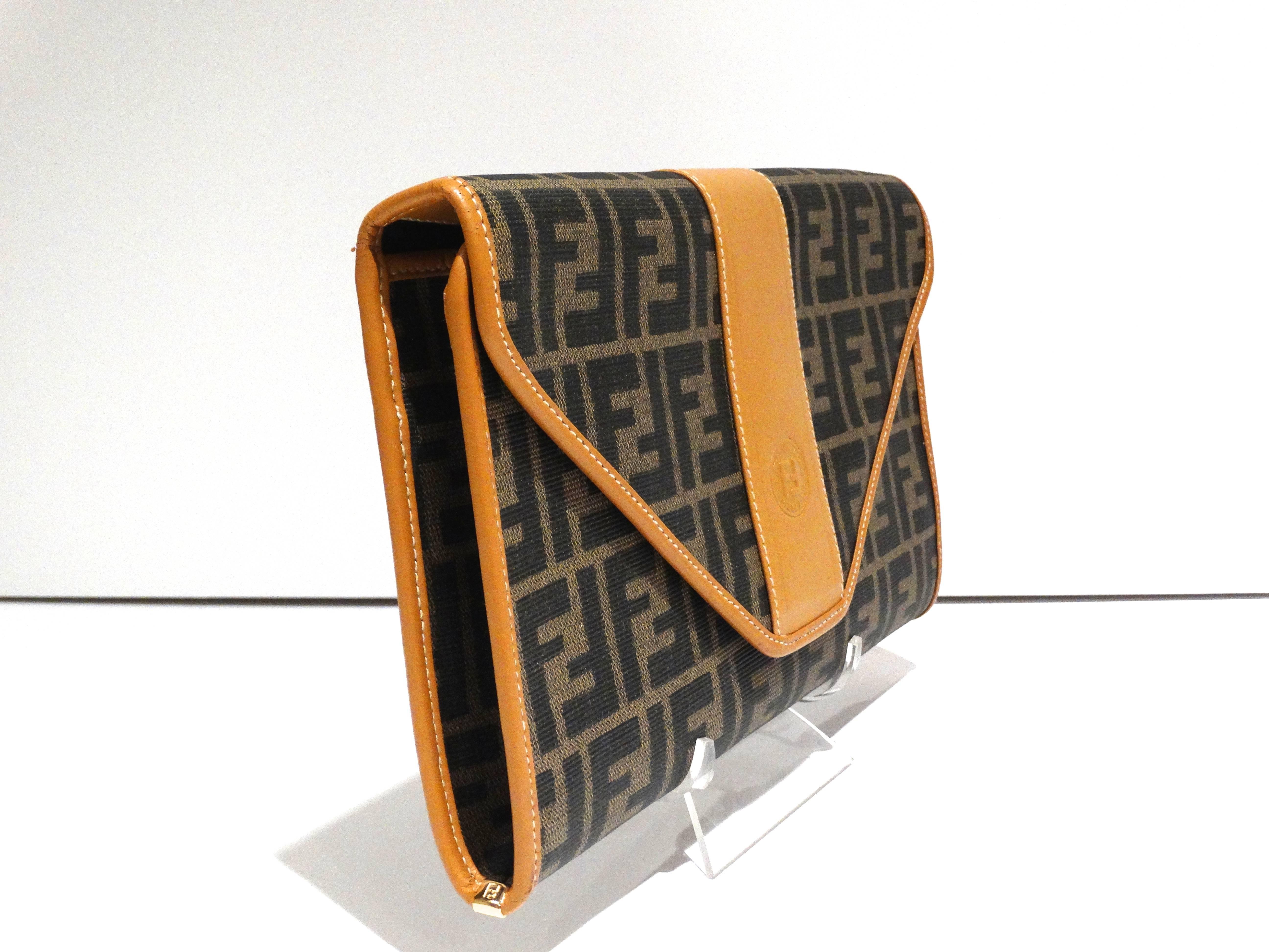 Classic 80's this is a fabulous monogram envelope clutch by Fendi. Trimmed in tan leather with gold accents and back zipper pouch. Has a detachable shoulder strap. comes with the original dust bag and is in like new condition. Classic Fendi print