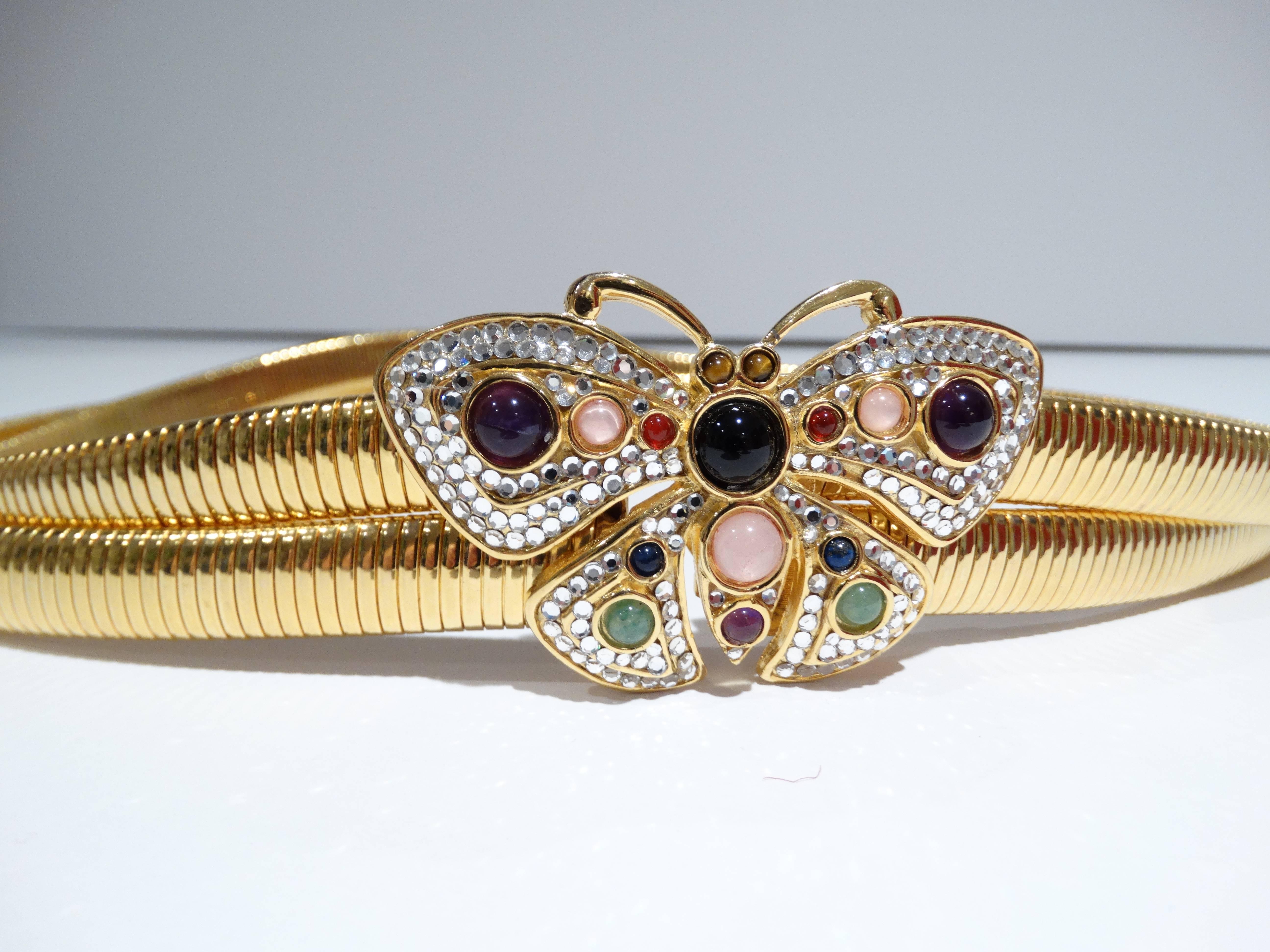 An adorable Judith Leiber butterfly belt encrusted with rose quartz, jade, black onyx and amethyst stones surrounded by clear crystals sit atop a gold tone double banded stretch belt. Circa 1980's belt measures 26 to 27 inches long. Butterfly