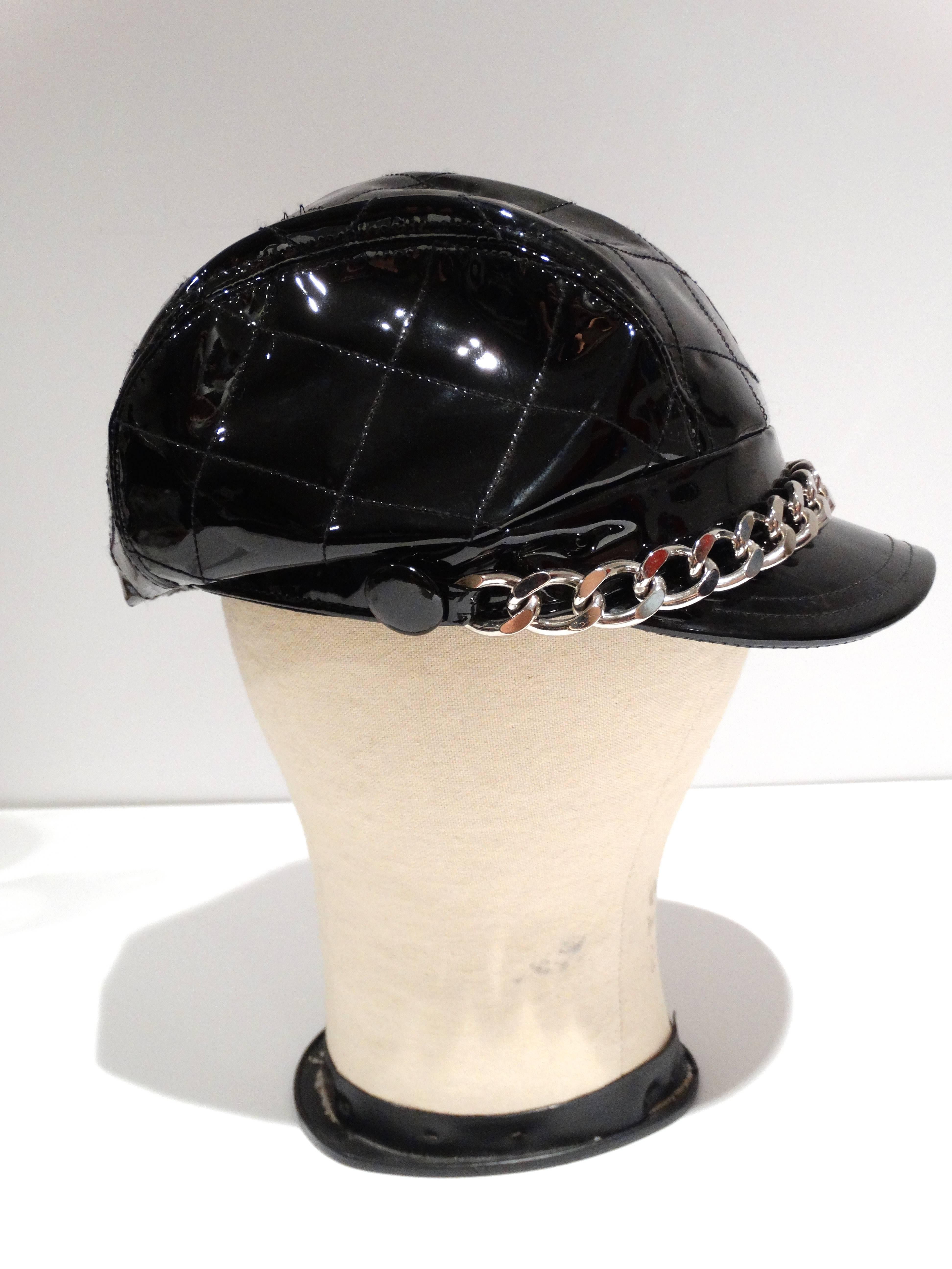 Oh so stylish 1990's Burberry newsboys cap in black patent. Features a large 1 inch chain across the front ... patient leather cap marked a size medium. lined in the classic Burberry fabric.  Fits a size 21