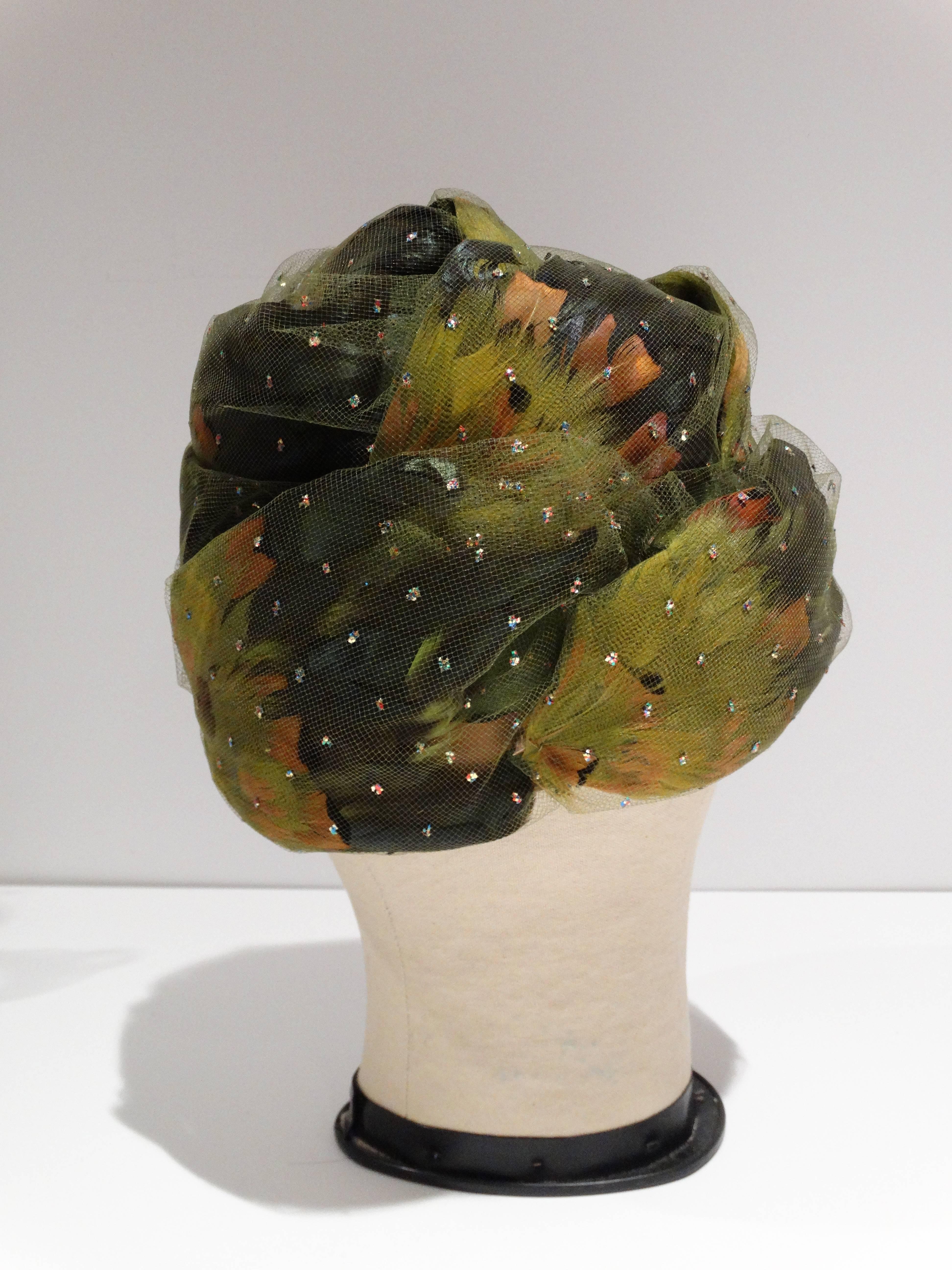Glorious Colored 1960's Pheasant feathered turban with a touch of sparkle, enrobed in a wispy green netting atop a beautifully rounded form... all of this and the Iconic Milliner's Label to add......Christian Dior!! This Turban is in Fabulous shape,