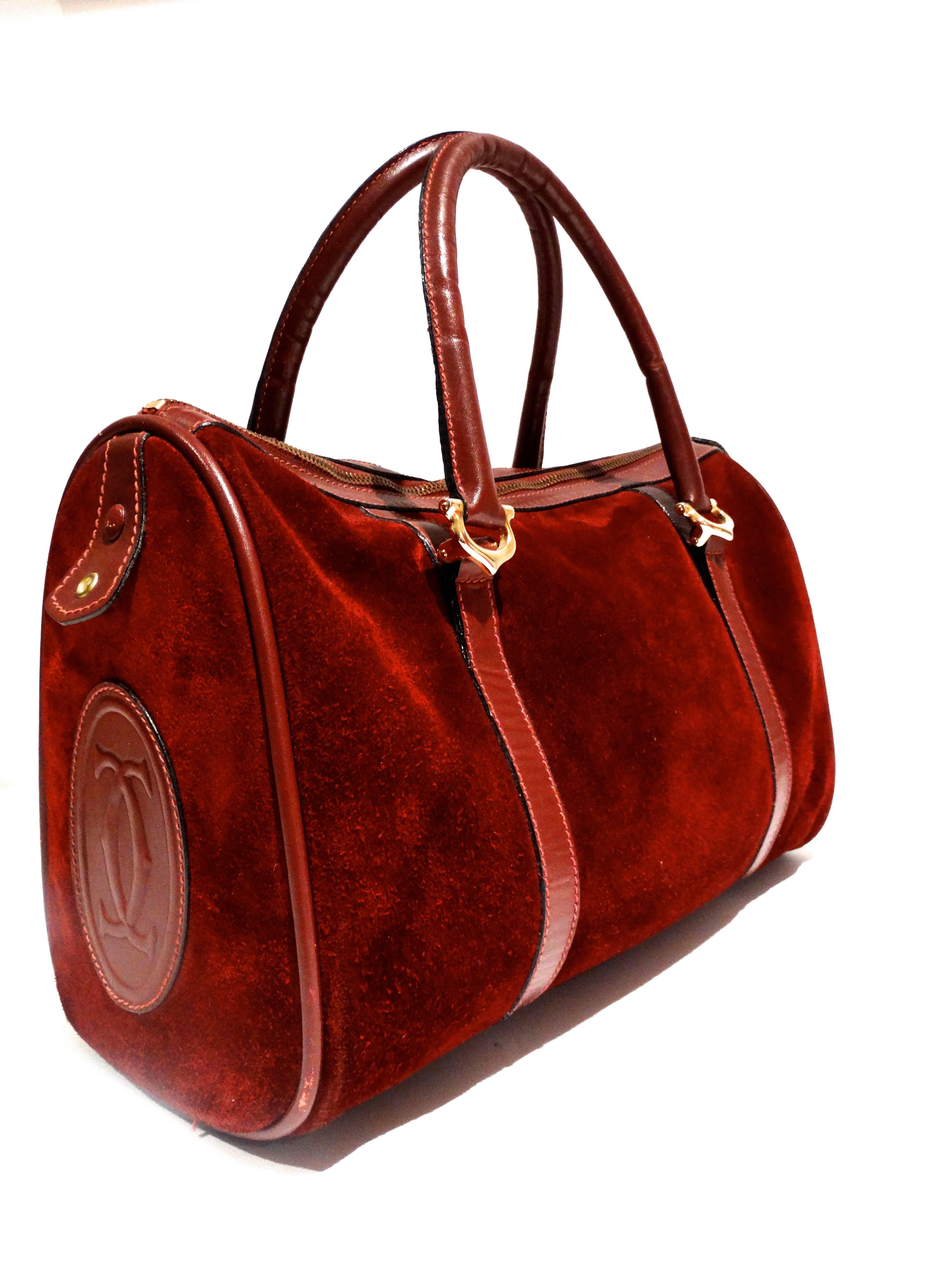 This beautiful Les Must de Cartier boston bag in Cartier Bordeaux suede leather is a rare sight. Top handles are in leather, main area is secured with zipper. Inside has matching textile lining and zipper pocket. Great statement handbag 

Made in: