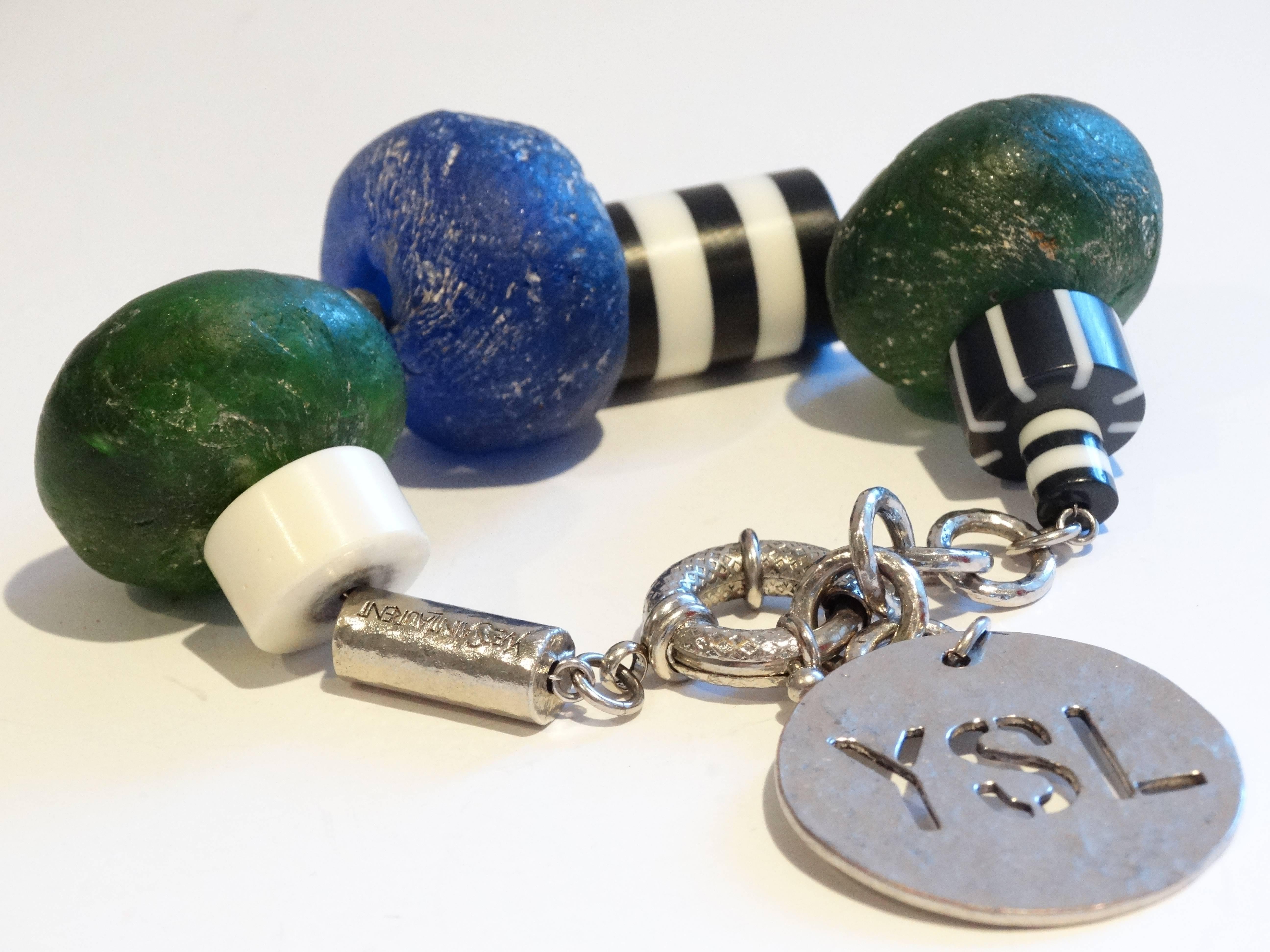 Super cool 1980's Yves Saint Laurent sea glass beaded bracelet with a huge YSL charm plate. Black and White Acrylic beads in between the blue and green sea glass. Strung on a think silver wire signed Yves Saint Laurent on one silver bead. Adjustable