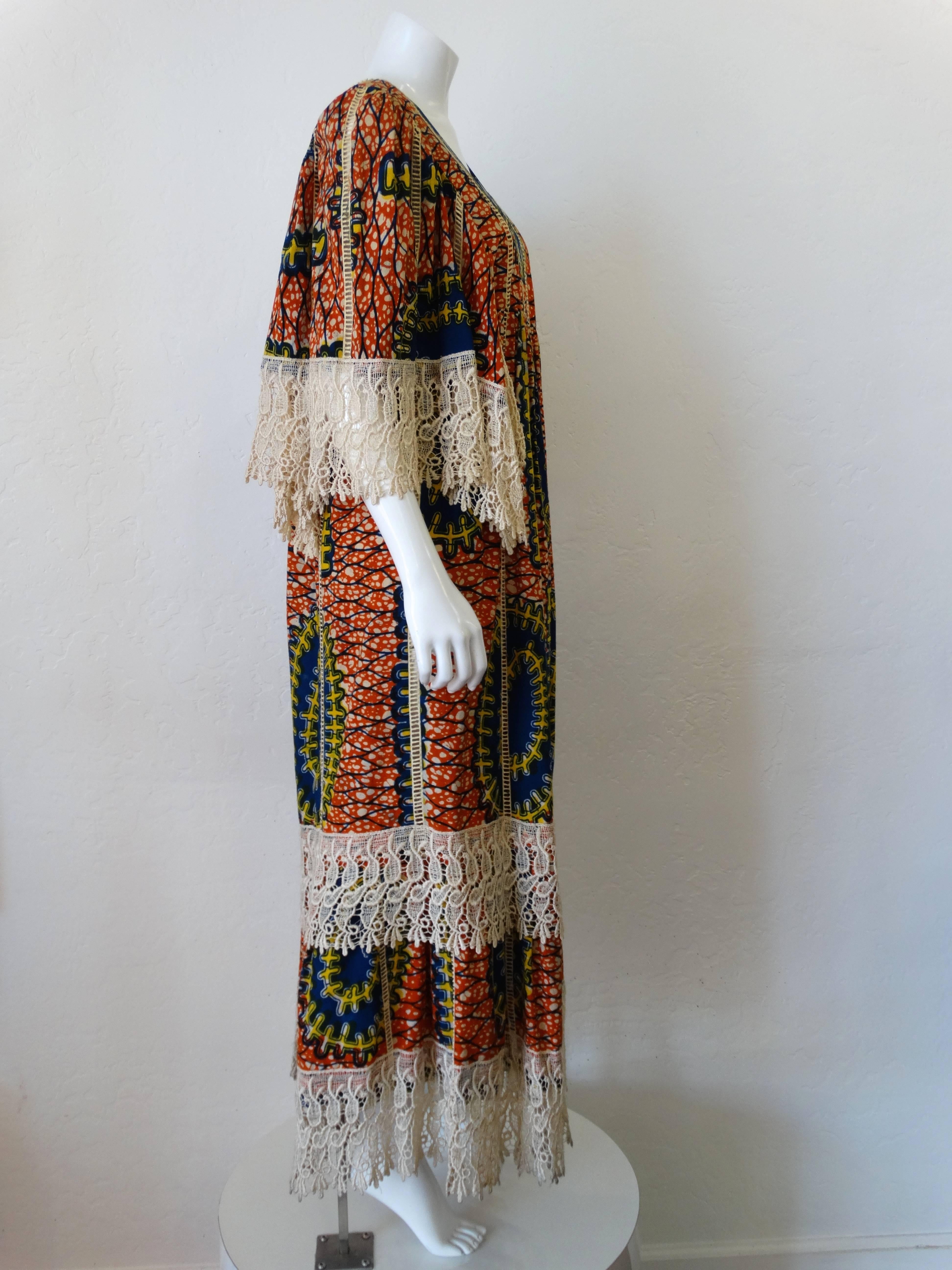 Handmade 1970s African viscose bohemian printed maxi dress. Viscose batik with dramatic cream crocheted lace details. Bold primary colored printed cotton. Maxi length with bell sleeves and empire waistline. Square neckline with tier lace details.