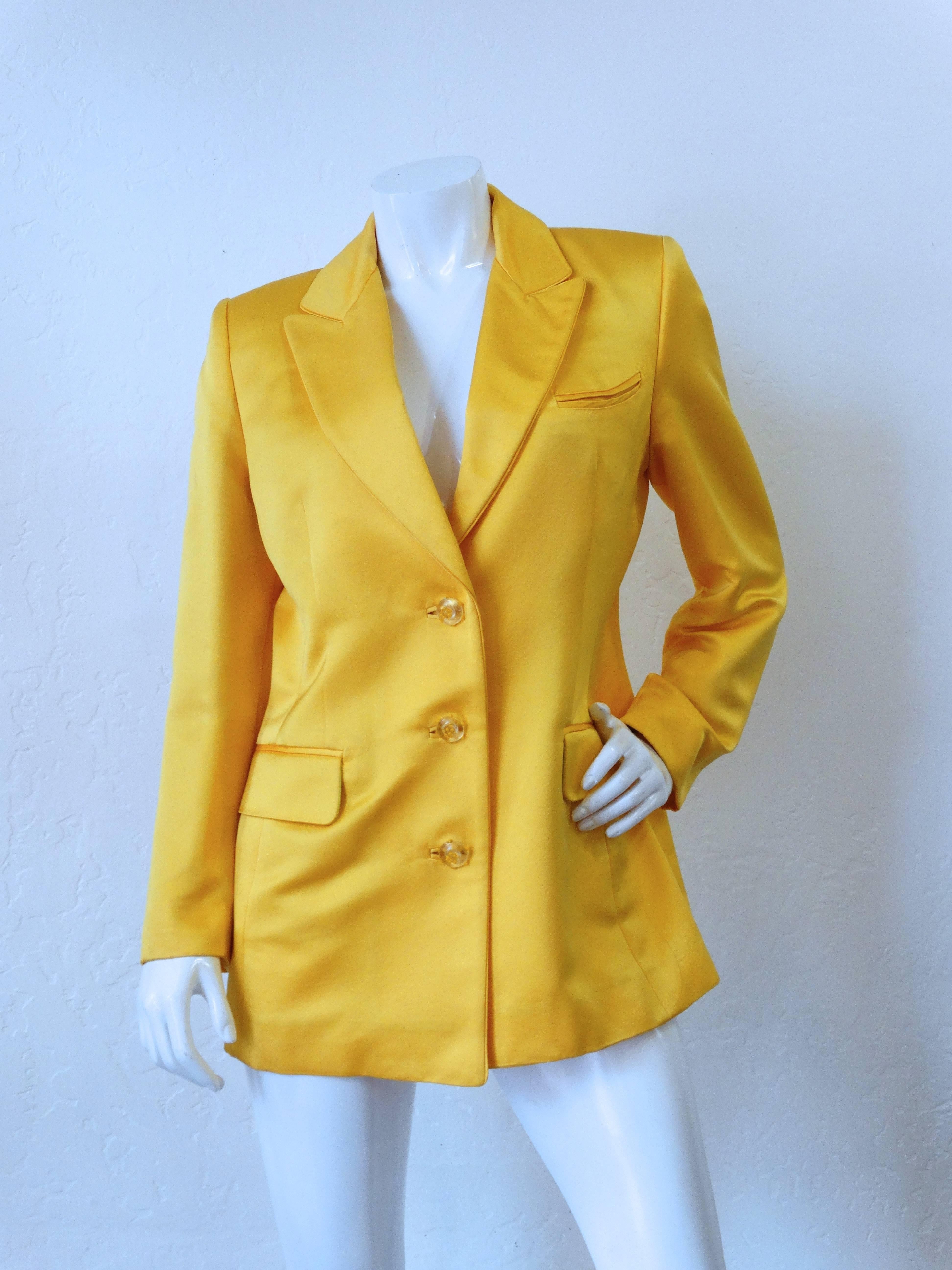 1980s Pam McMahon Blazer in a Primerose Yellow Satin. Classic tailored fit. Unique glass button closure up the front. Pockets at either side of the waist. Green piping on the interior. Marked sz 44 

Measurements 
Bust: 17