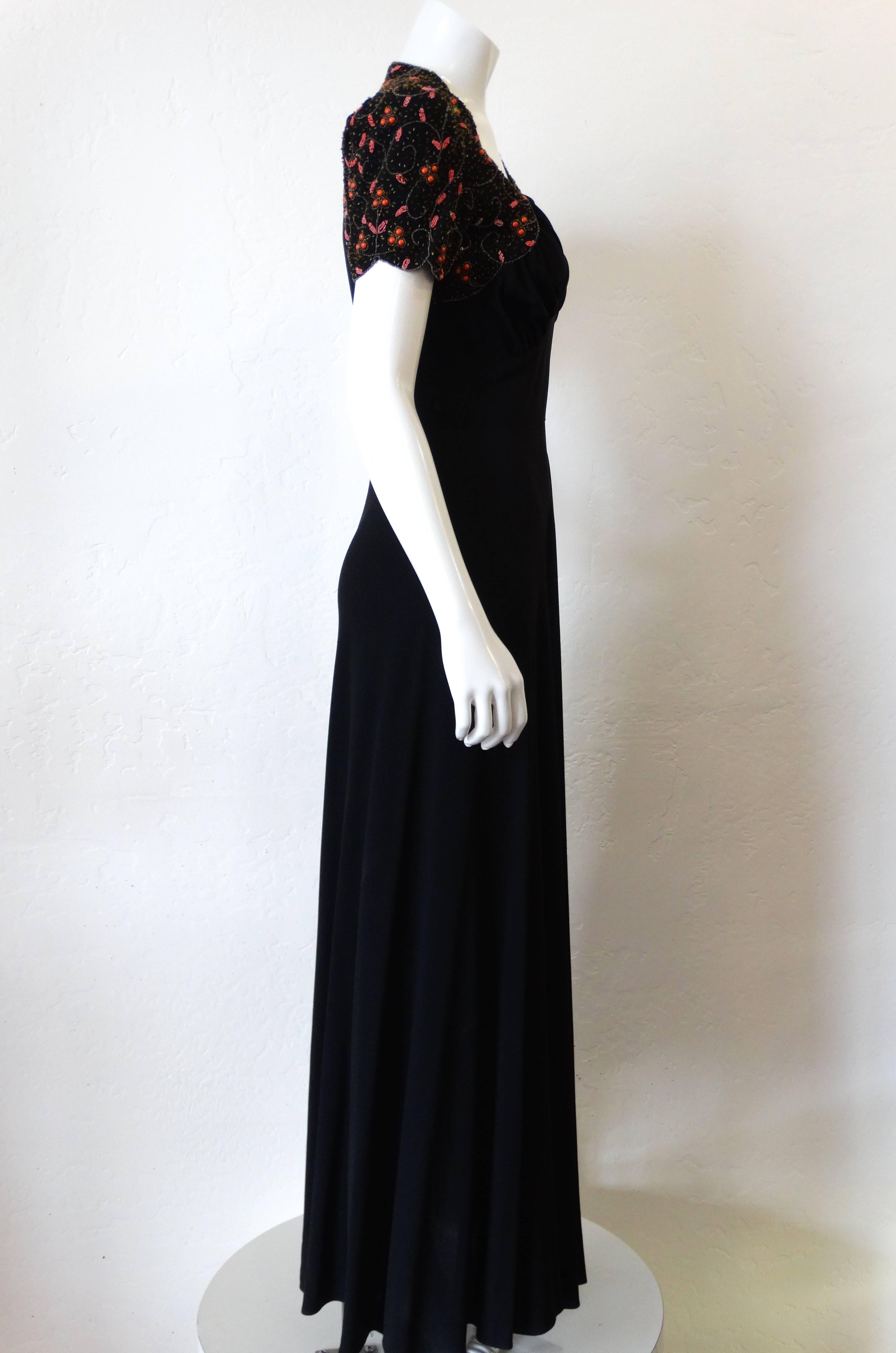 The most amazing 1940s glass beaded gown! Classic 40s silhouette with short sleeves and sweetheart neckline. Slightly sheer black Rayon with orange and pink botanical beading on the shoulders. Flattering ruched bustline. Zips up the side. Fits a