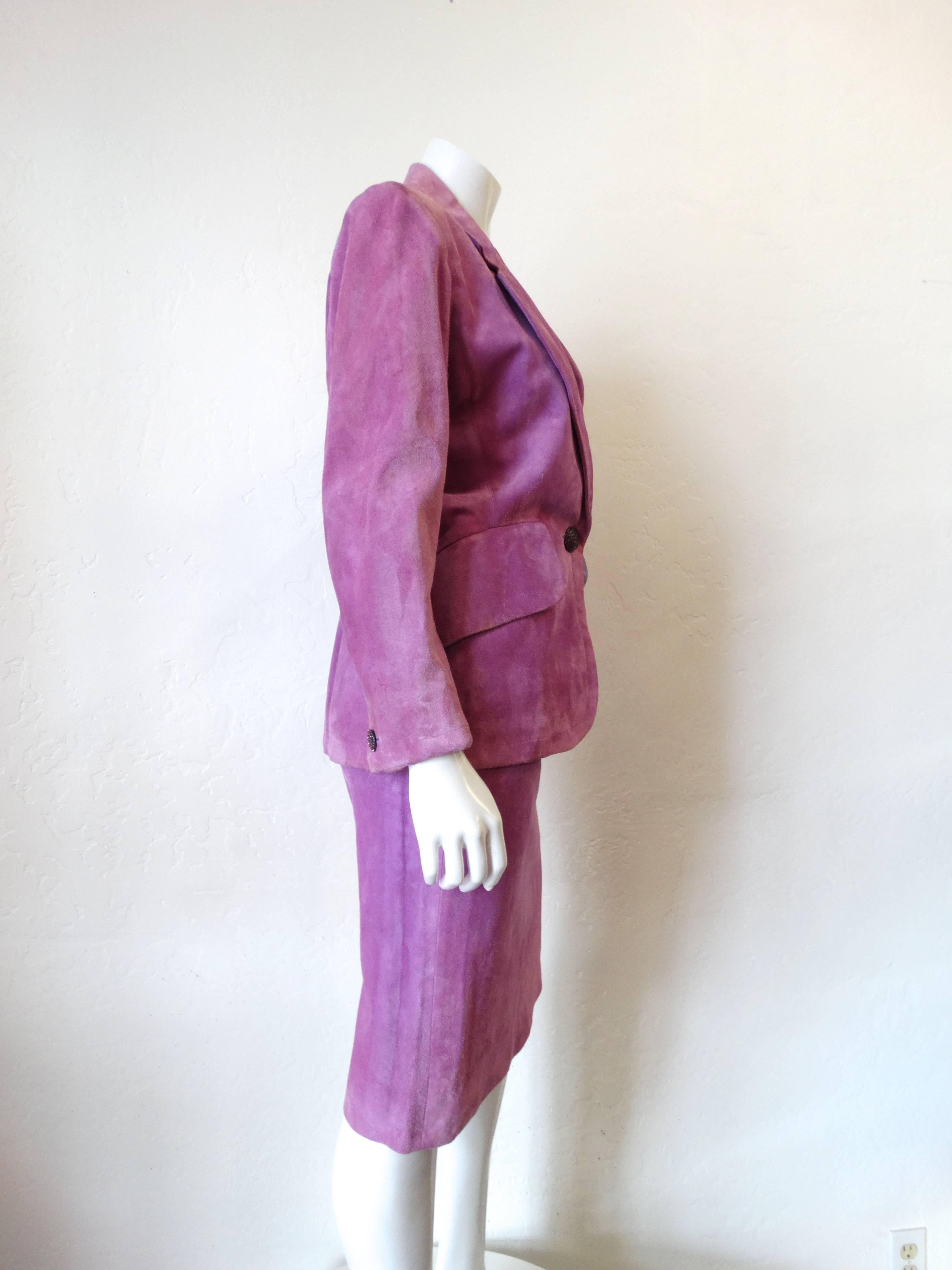 The ultimate Saint Laurent power set! Straight from the 1980s- this set comes in a brilliant lilac suede complete with rhinestone encrusted buttons! Pockets at blazer's waist as well as the skirt's hips. Fully lined silk interior. Skirt zips up the
