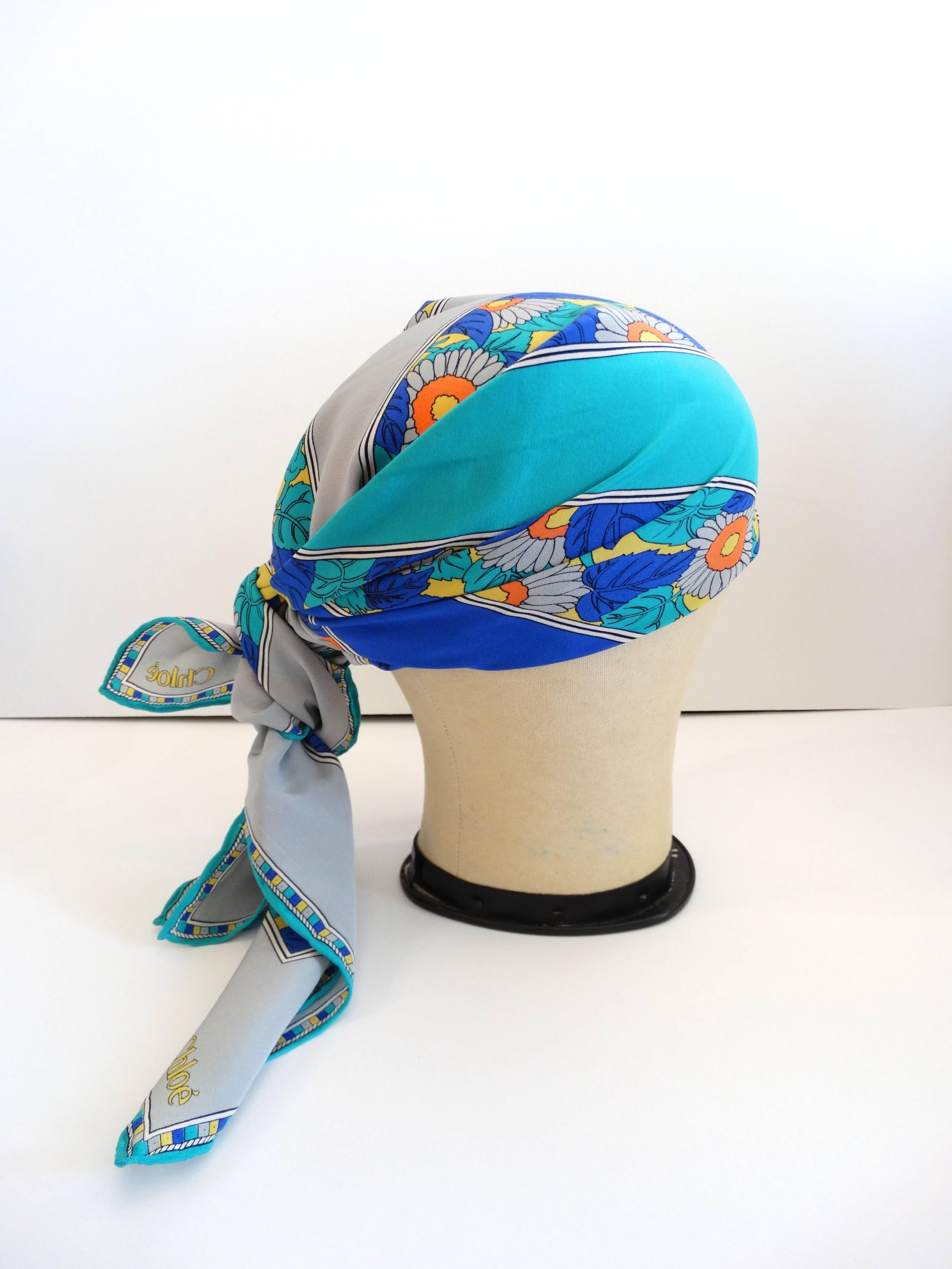 Chloe silk scarf in a bright, exciting floral for Spring! Hues of royal blue and turquoise accented with bursts of orange and yellow- this scarf is the perfect pop of color for any outfit. Easily worn knotted around the neck or as a headscarf! Hand