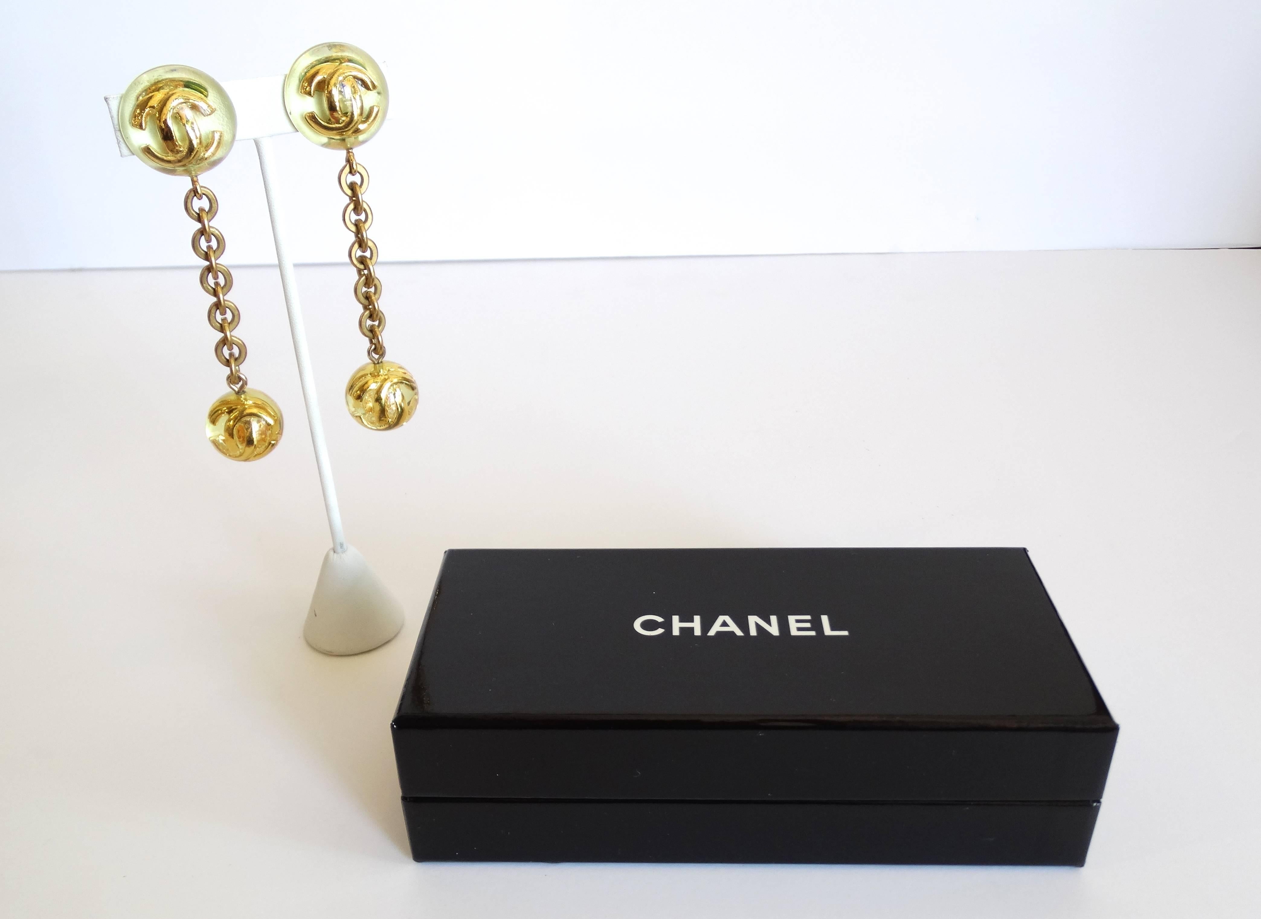 How fabulous?! Classic 1980's pair of Chanel Lucite Ball Drop Earrings! These feature the CC Chanel logo suspended in clear lucite- dangling from thick gold chains. Clip on backs. Comes with original box. Made in France  stamped 25 