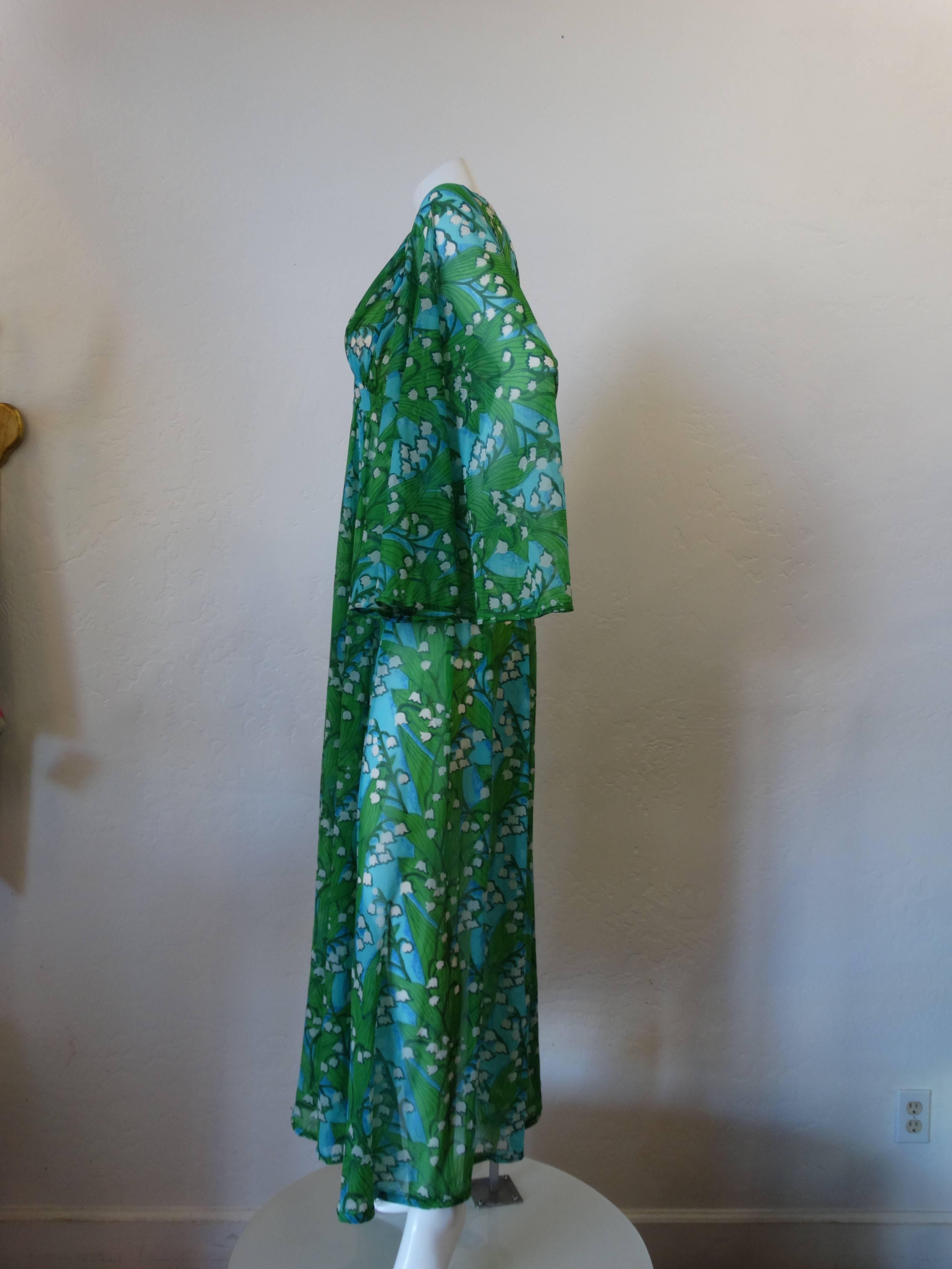This dress is absolutely stunning! Beautiful bold and bright colors showcase delicate Lily of the Valley flowers with green leaves on a blue background. There is a tag that says Robert David Morton along the inside attached to the zipper. The zipper