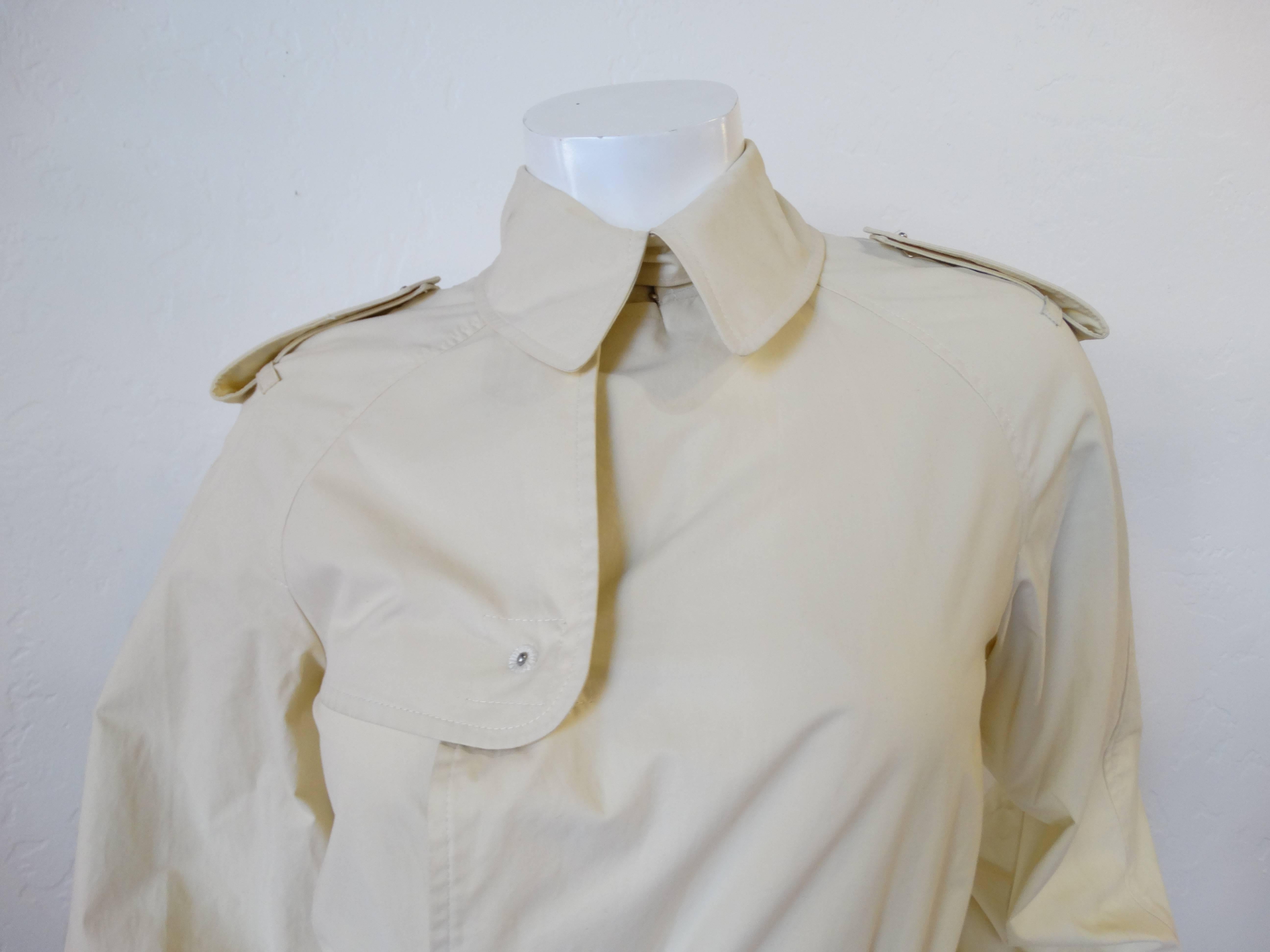 Adorable manteau Jean Paul Gaultier des années 90 ! Un trench de longueur mini dans un tissu beige crémeux. Accentué par des fermetures à pression uniques au niveau du buste, de l'encolure et des poignets. Des attaches à la taille pour un look plus