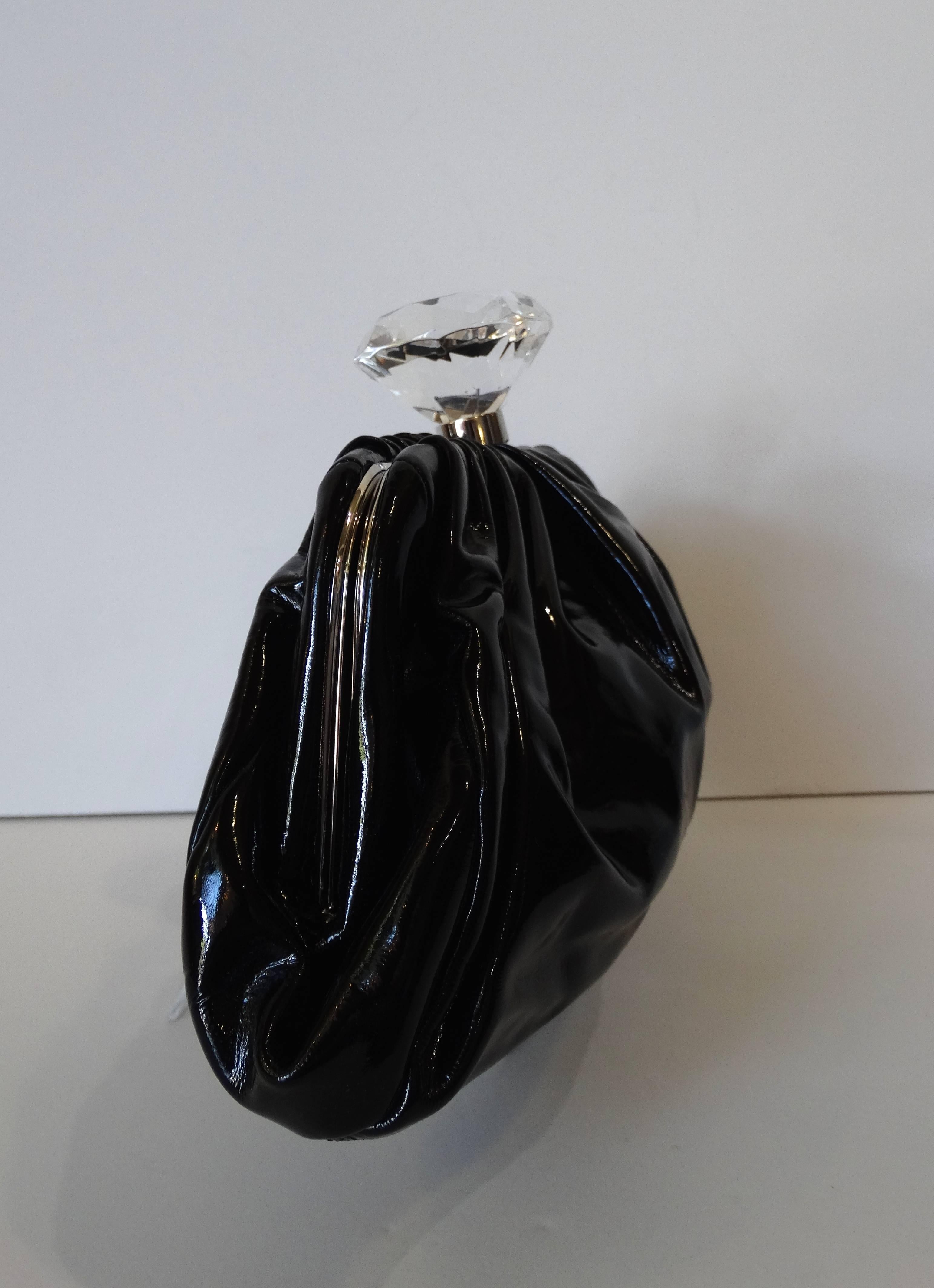 Forget the Hope diamond- we want Chanel diamonds! This incredible clutch comes a soft and shiny black patent leather- accented with silver hardware and of course: an oversized lucite diamond with CC logo inside. Push lock closure at the top. Fully