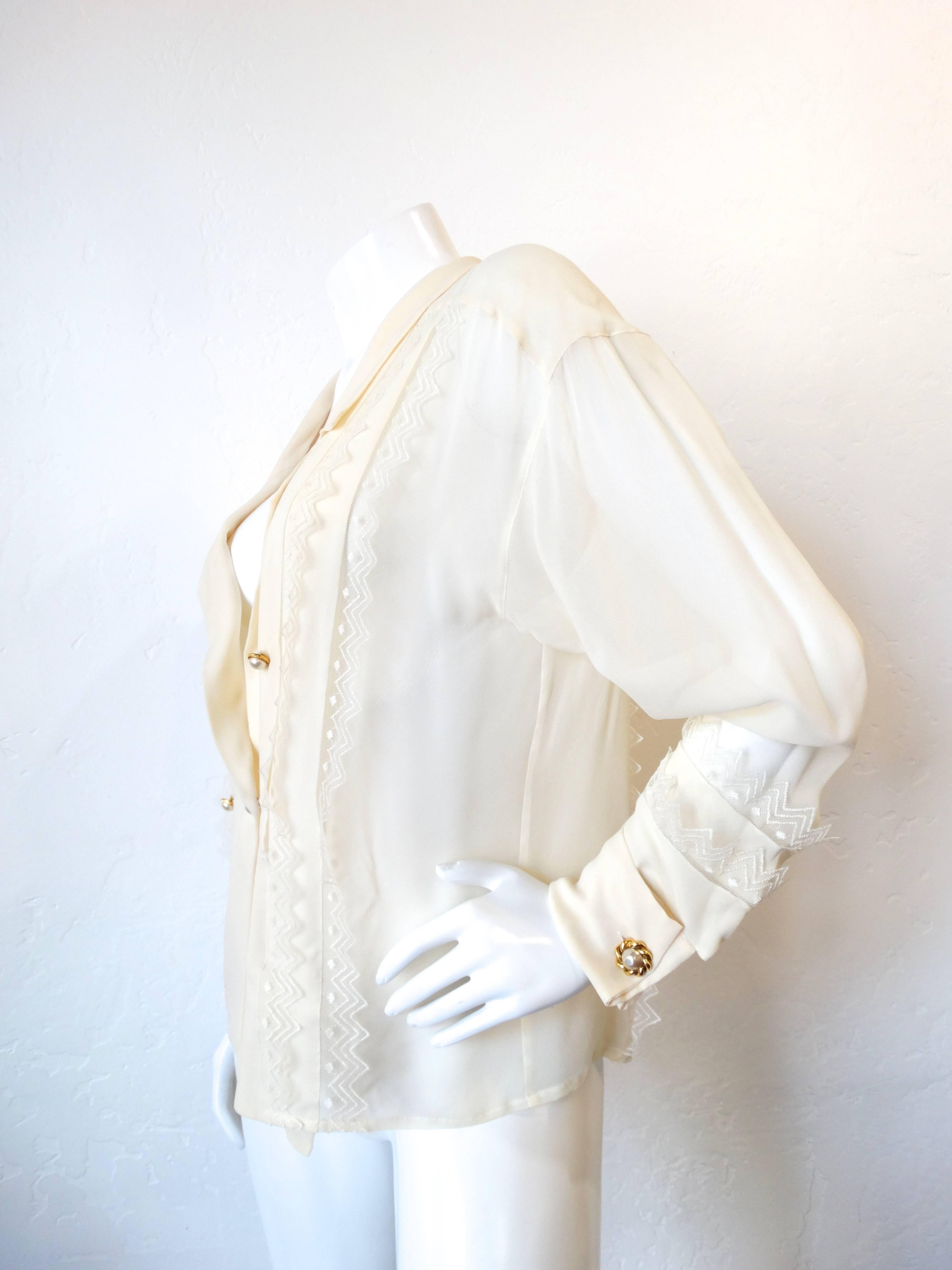 Incredible Chanel blouse from the 1980s. Semi-sheer cream fabric accented with gold metal and faux pearl buttons. Tiered ruffle applique lace details along the bodice and cuffs. Some light wear along the edge of the collar. 

* Chanel cufflinks are