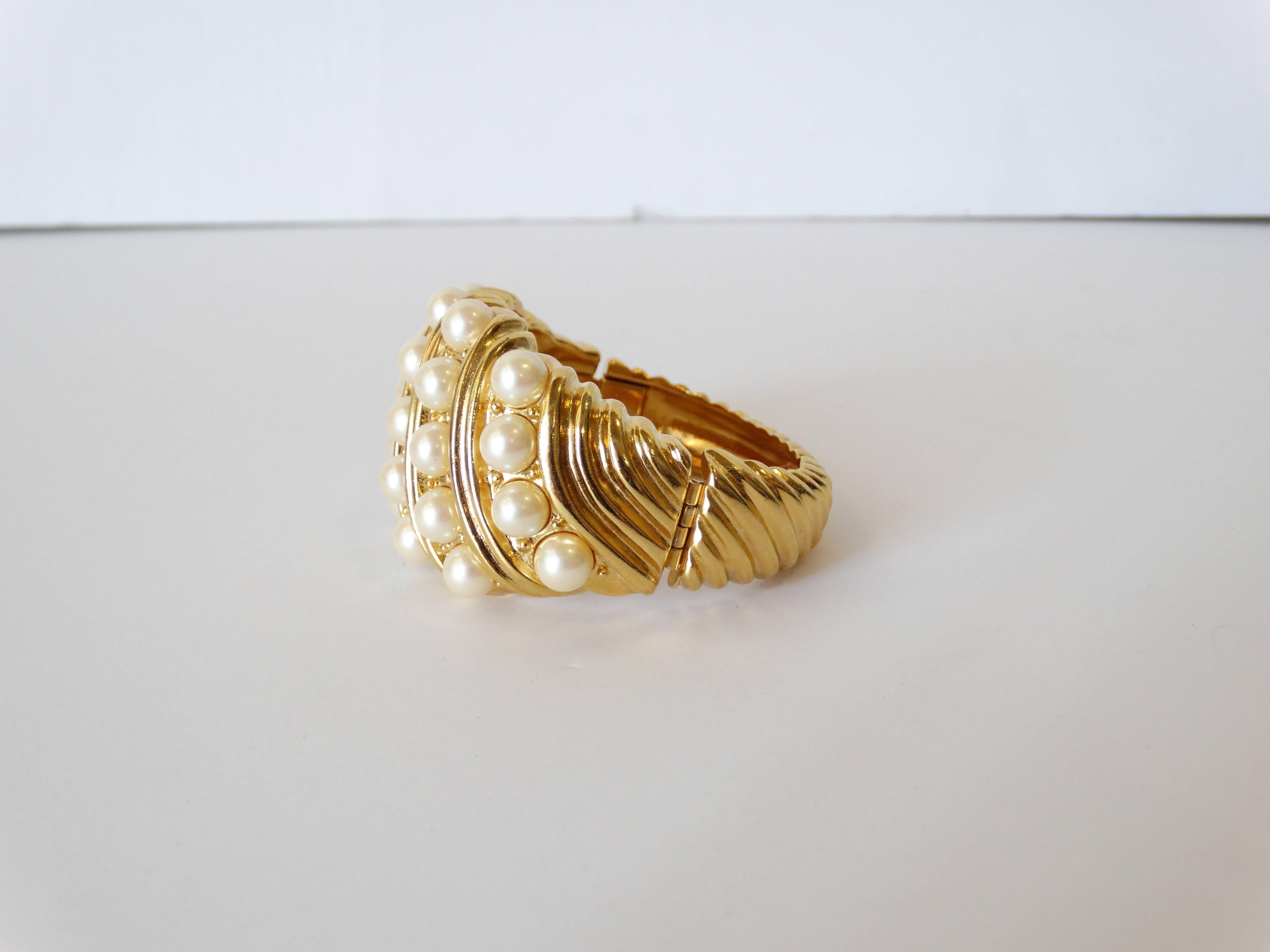Yves Saint Laurent cuff cast in a brilliant gold metal. Banded with 5 rows of faux pearl accents. Box clasp closure on the side. Signed at the back YSL
