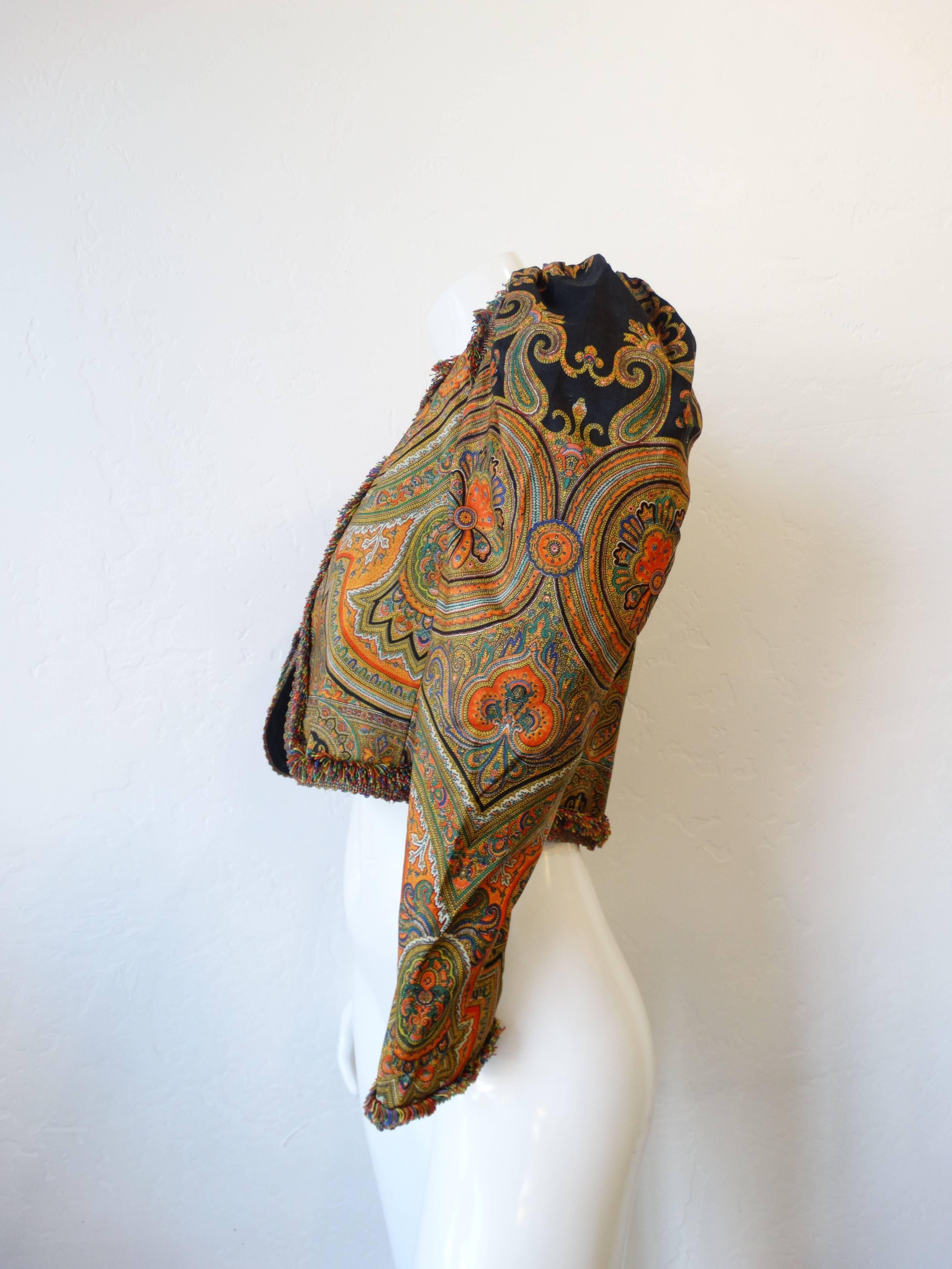 Psychedelic paisley printed jacket from the 1970s. Made by Muriel Grateau, French designer. 100% silk print accented with rainbow woven ribbon fringe all along the edges of the jacket. Worn open, fits a ranges of sizes though its marked a French
