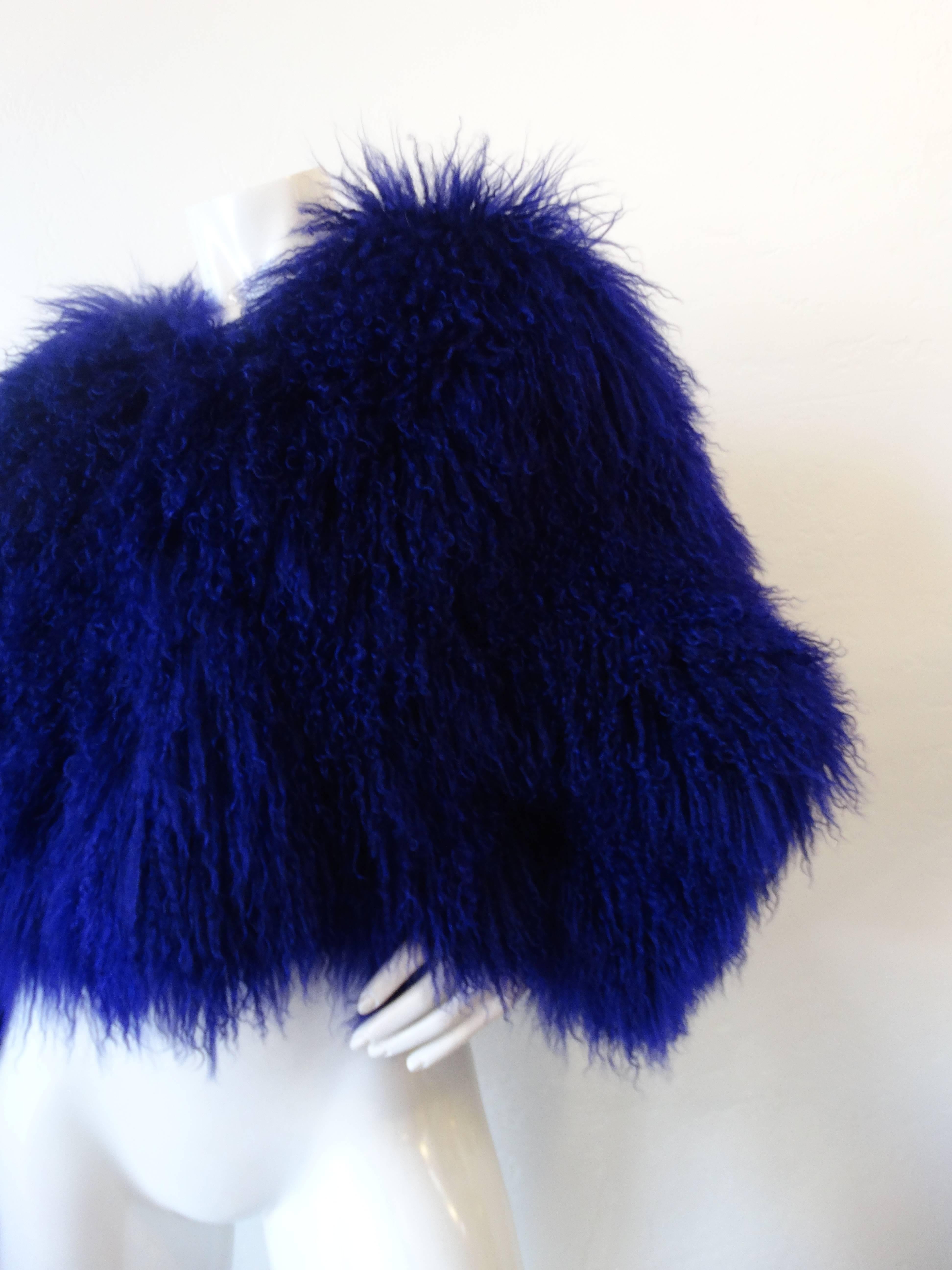Superbe manteau en fourrure d'agneau de Mongolie des années 1980:: de couleur violette:: avec un col rond et une fermeture par boutons crochets. Ce manteau glamour a des épaules exagérées:: des poches latérales et est entièrement doublé en soie