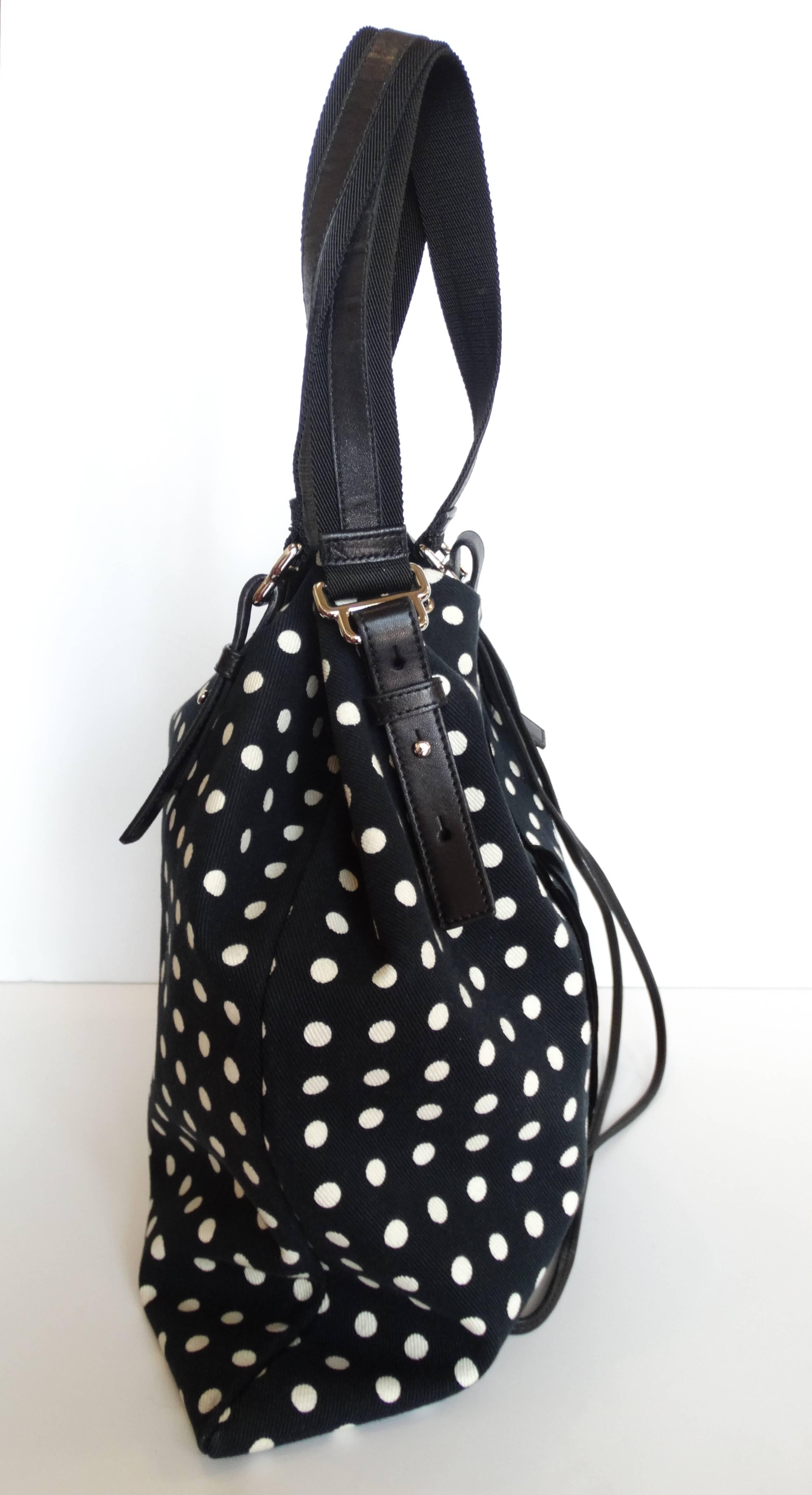 Black and white polkadot printed canvas with leather straps and details. Black velvet YSL signature down the front of the bag. Top cinches in with leather drawstring strap. Silver hardware, Satin lined interior with zip pouch in the side.