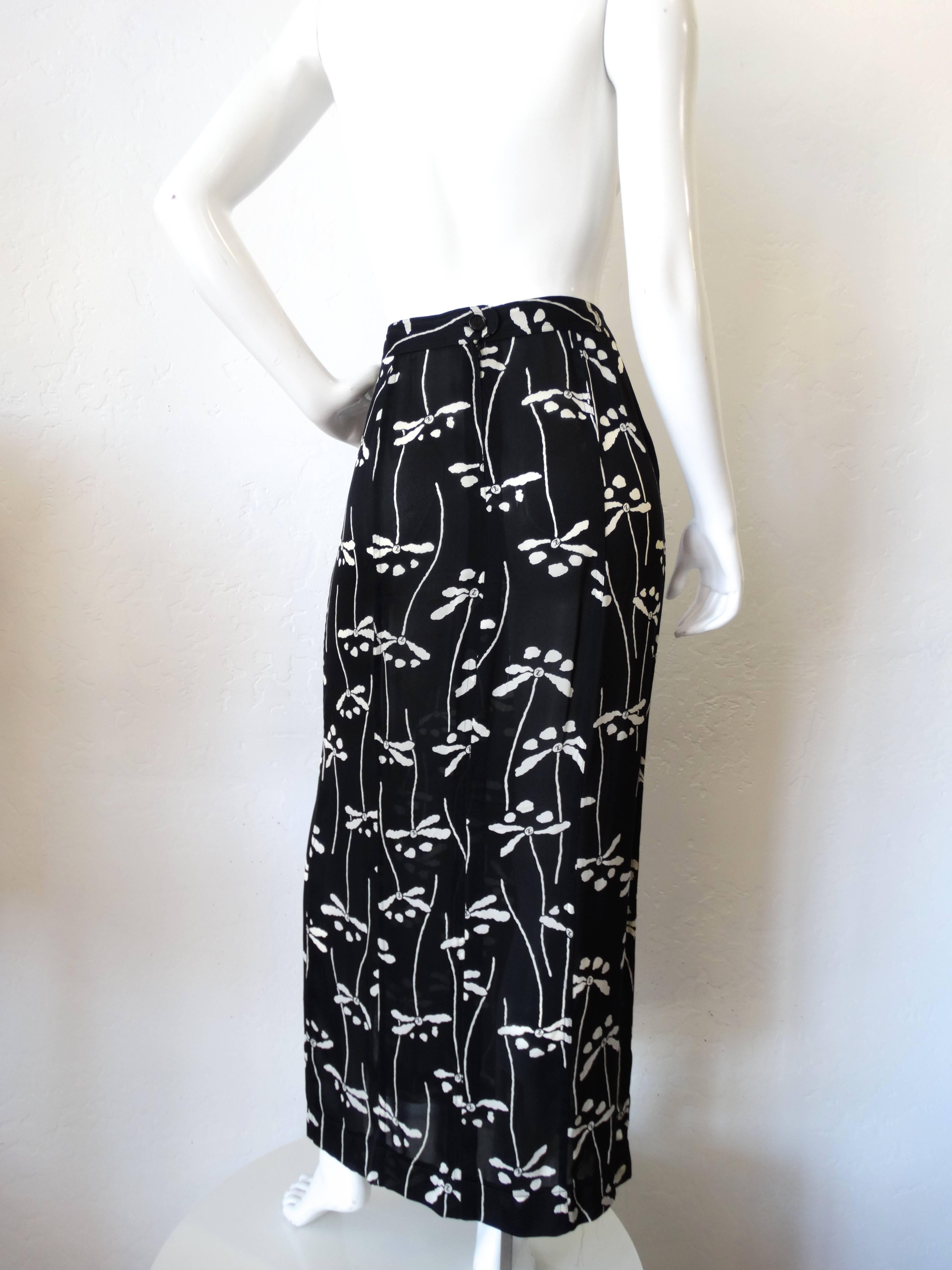 Incredible 1990s Chanel Floral Skirt! Fitted waist with a pencil skirt like fit, a knee length slit along the left leg. Adorable black and white floral print accented with CC logos on the inside on 100% silk fabric. Zips and buttons up the back.