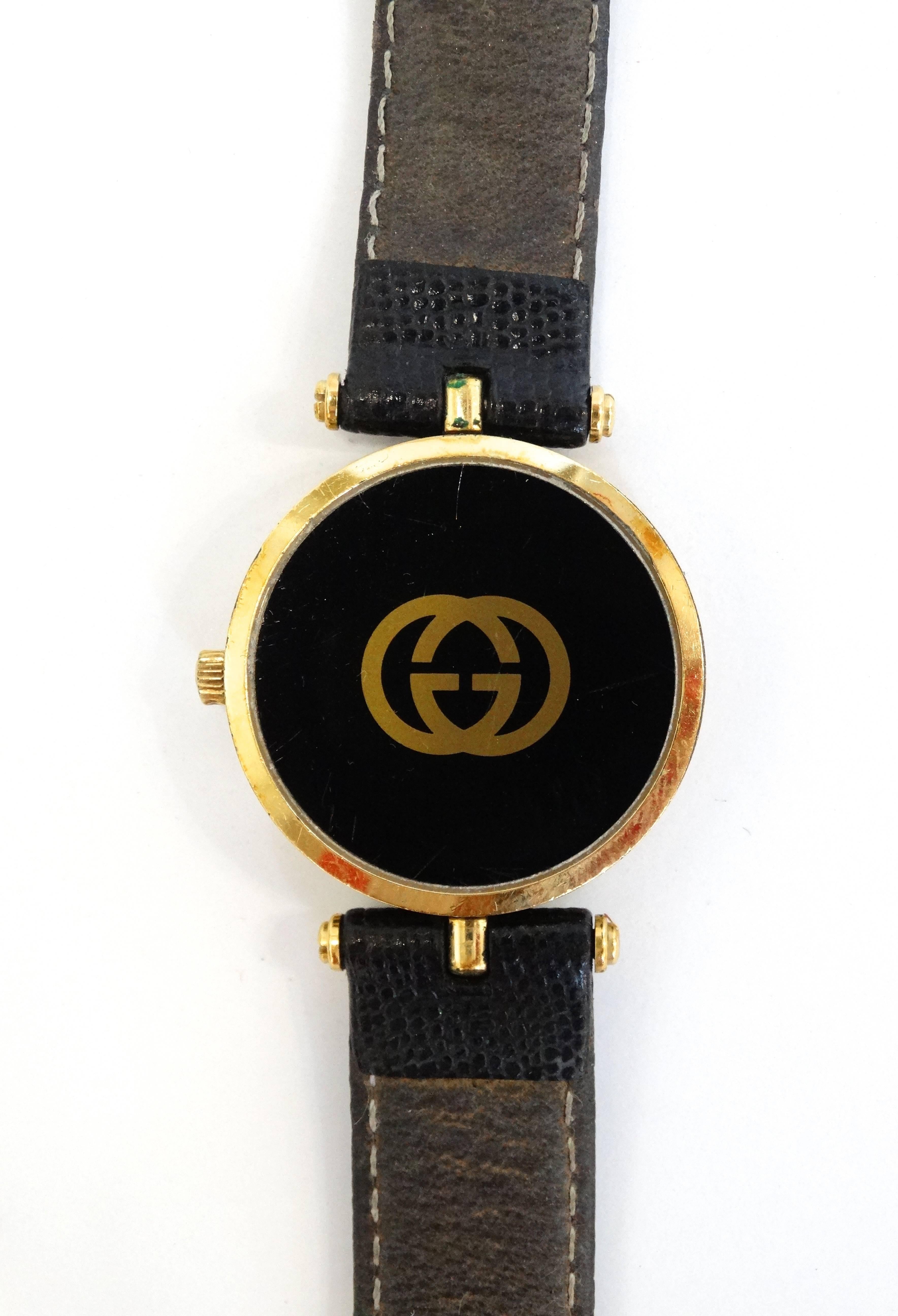 1980s watch from the iconic brand Gucci! Solid black with gold roman numerals on the face. Hardware cast in gold metal accented with black enamel stripes on the side. Buckle embossed with the classic GG logo, signed with Gucci on the back. Black