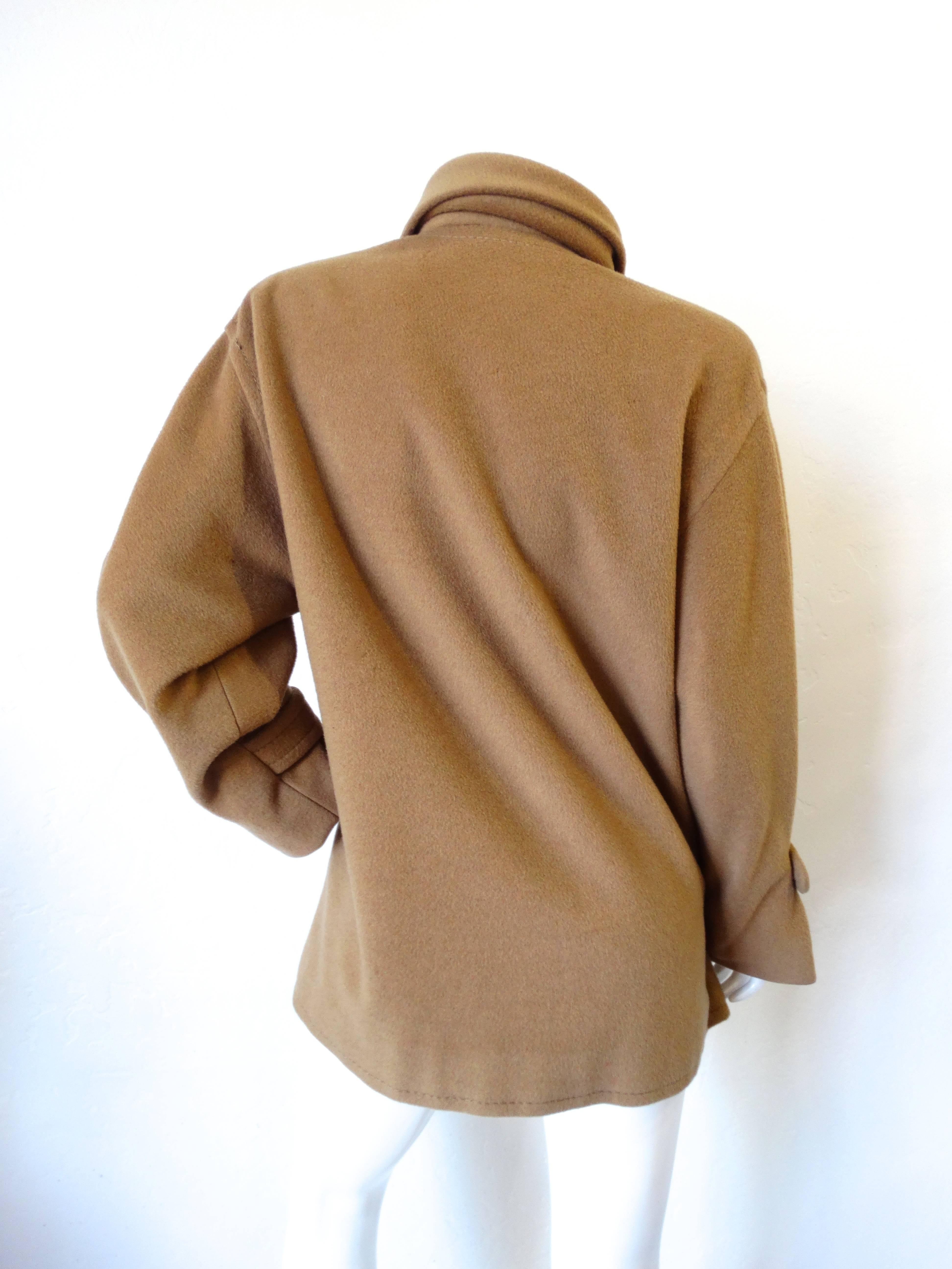 Keep cozy in our fabulous coat from James Galanos- an accomplished designer of haute French couture! This fabulous jacket is from the 1980s! Soft, thick wool blend in a rich tan color. Gathered neckline with double gold button closure. Sleeves are