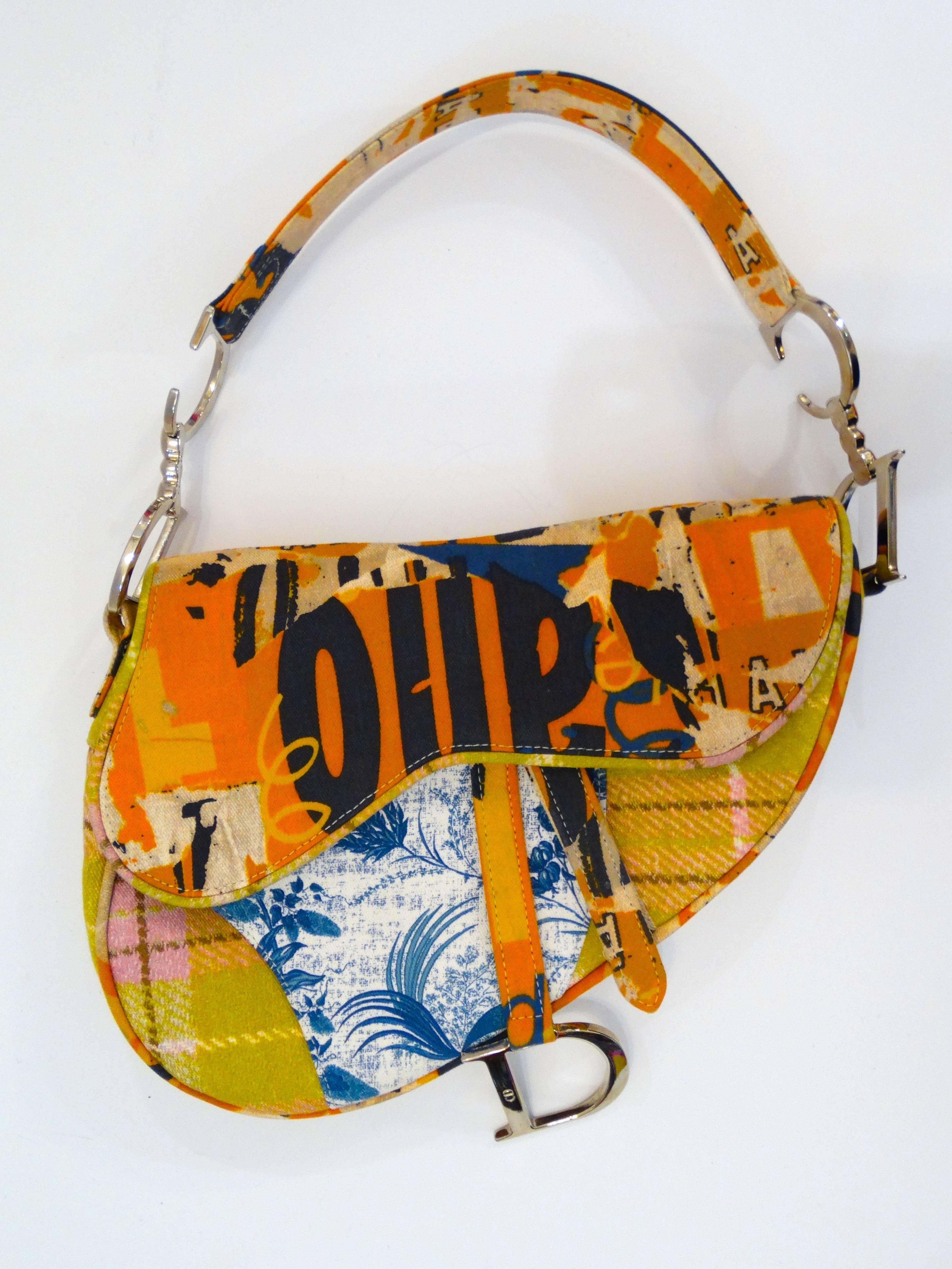 Saddle bags are back- in style, that is! The iconic Christian Dior Saddle bag of the 2000s in a bold multicolored graphic pattern. Signature CD silver hardware strap and matching Dior accent suspended from the bag closure. Top flap opens to reveal