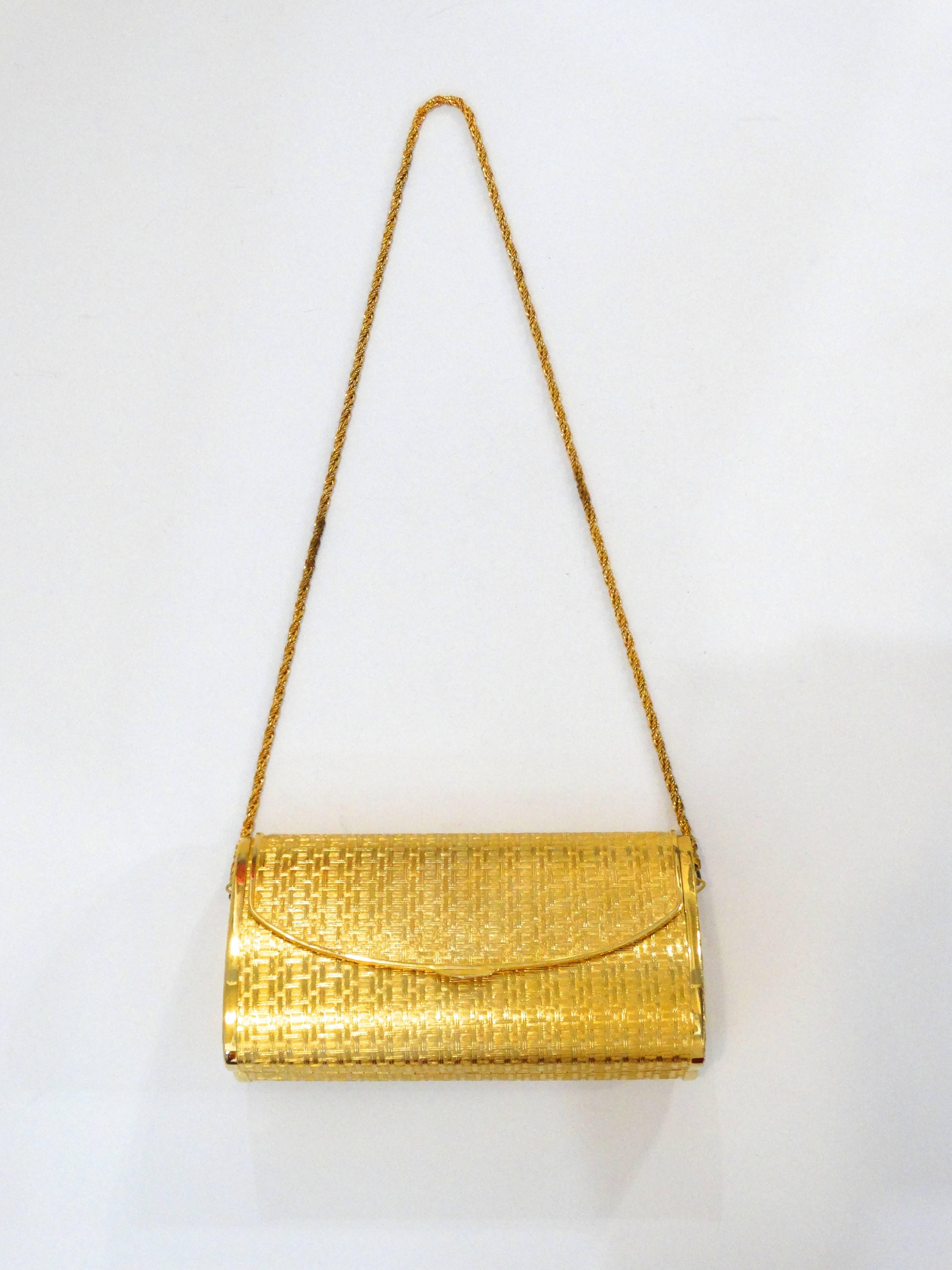 Take on the night with our incredible 1960s gold evening bag from Saks Fifth Avenue! Brushed gold metal with basket weave like texture embossed into it. Hard shell metal casing with soft fabric lined interior. Matching gold strap that is easily