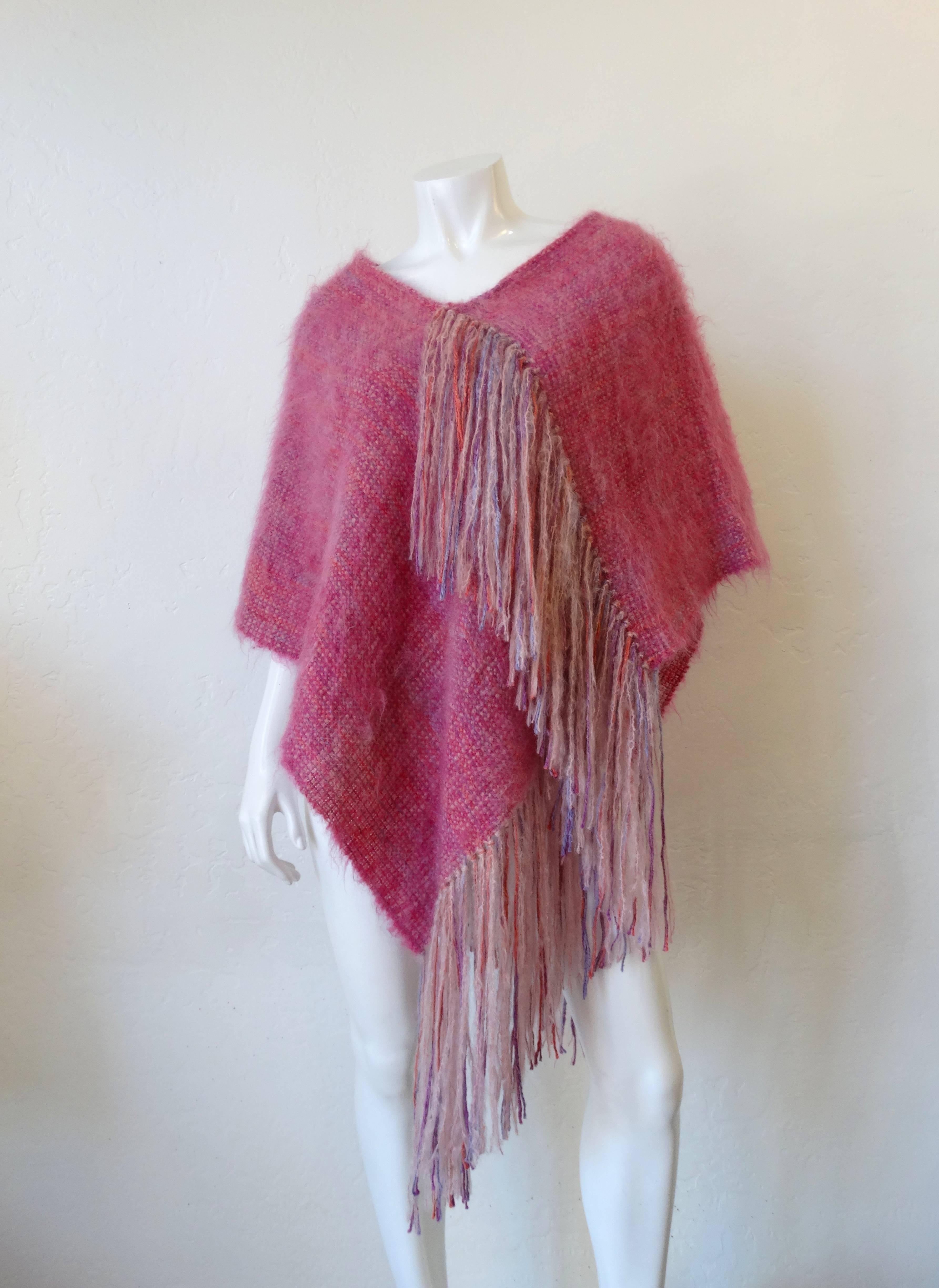 Can you believe this piece is HAND-WOVEN? Crafted in the 1990s by Crane Day Hand-weaver made from a fluffy, mohair fibrous yarn! Solid pink poncho with long purple, pink and white fringe. Open sizing, so everyone can enjoy! The inspiration comes