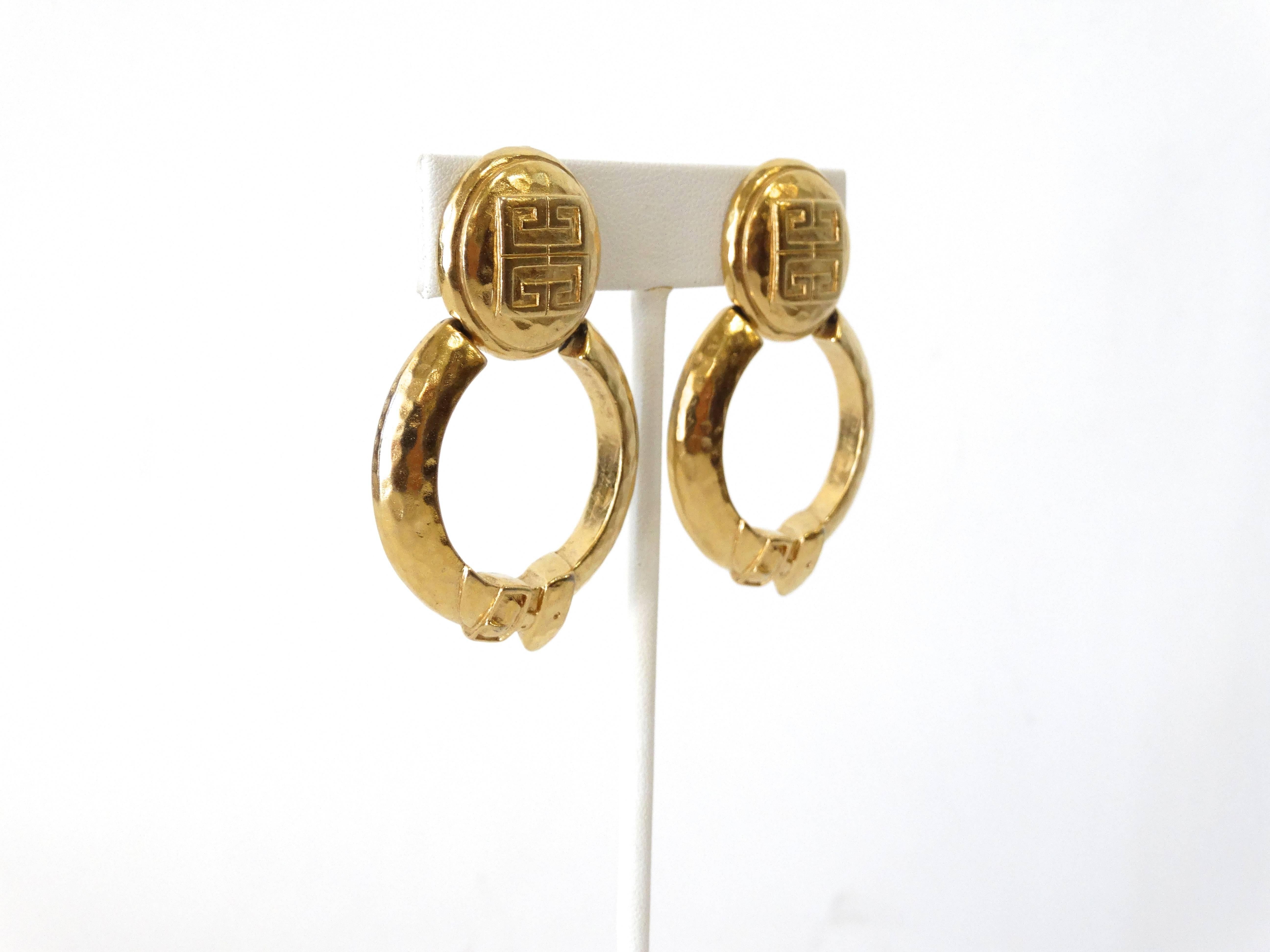 Rock a statement earring in our 1980s Givenchy door-knockers! Brilliant gold metal with a hammered finish. Hoop style door knocker earring with unique belt details. Embossed with the Givenchy G logo on the buttons. Signed Givenchy on the back of the