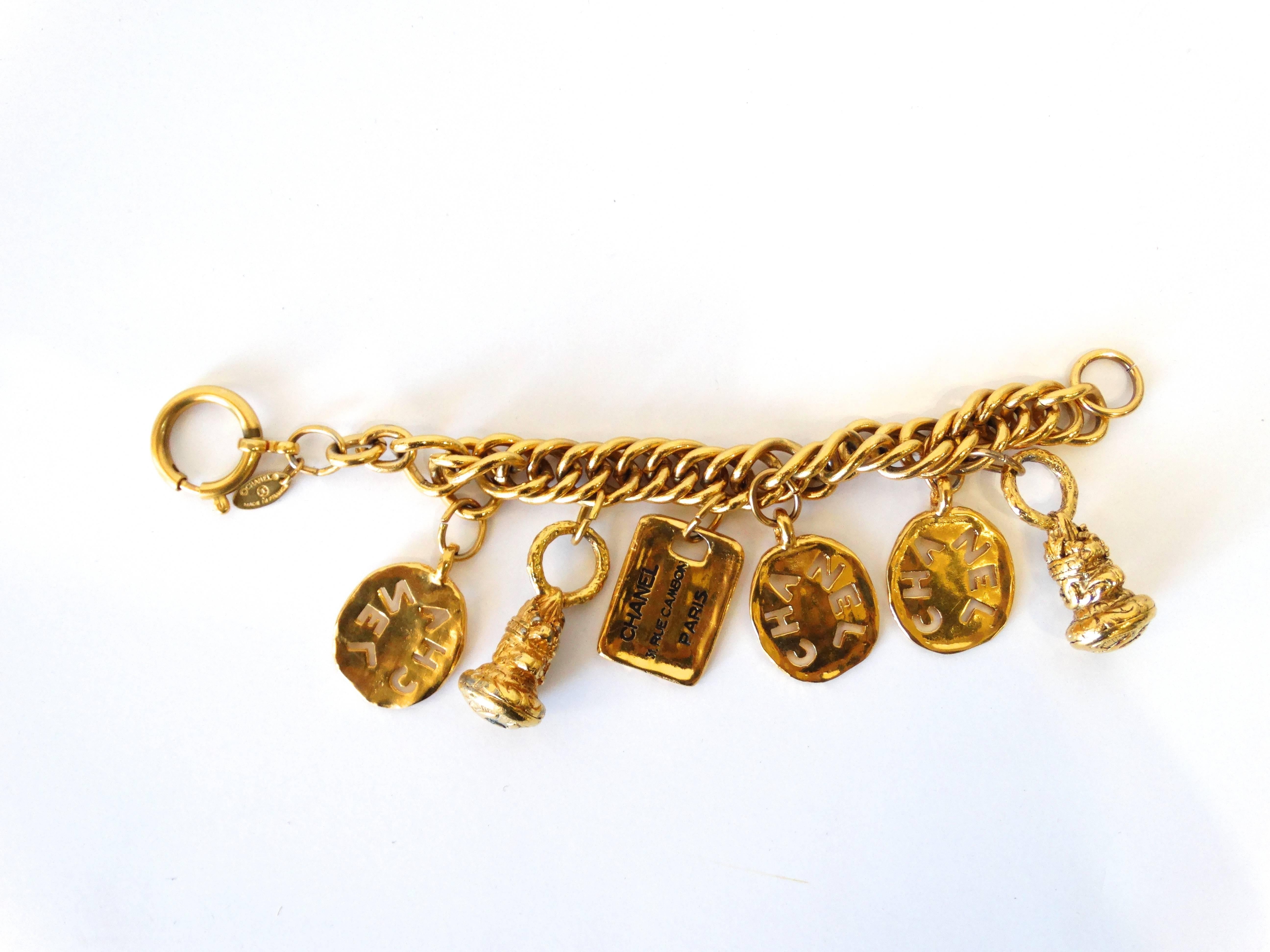 Get charmed by our 1980s Chanel charm bracelet! Thick gold metal chain accented with a bunch of matching oversized Chanel baubles! Super cool cut-out charms emblazoned with logos. Simple lobster clasp closure. Signed Chanel placard next to the