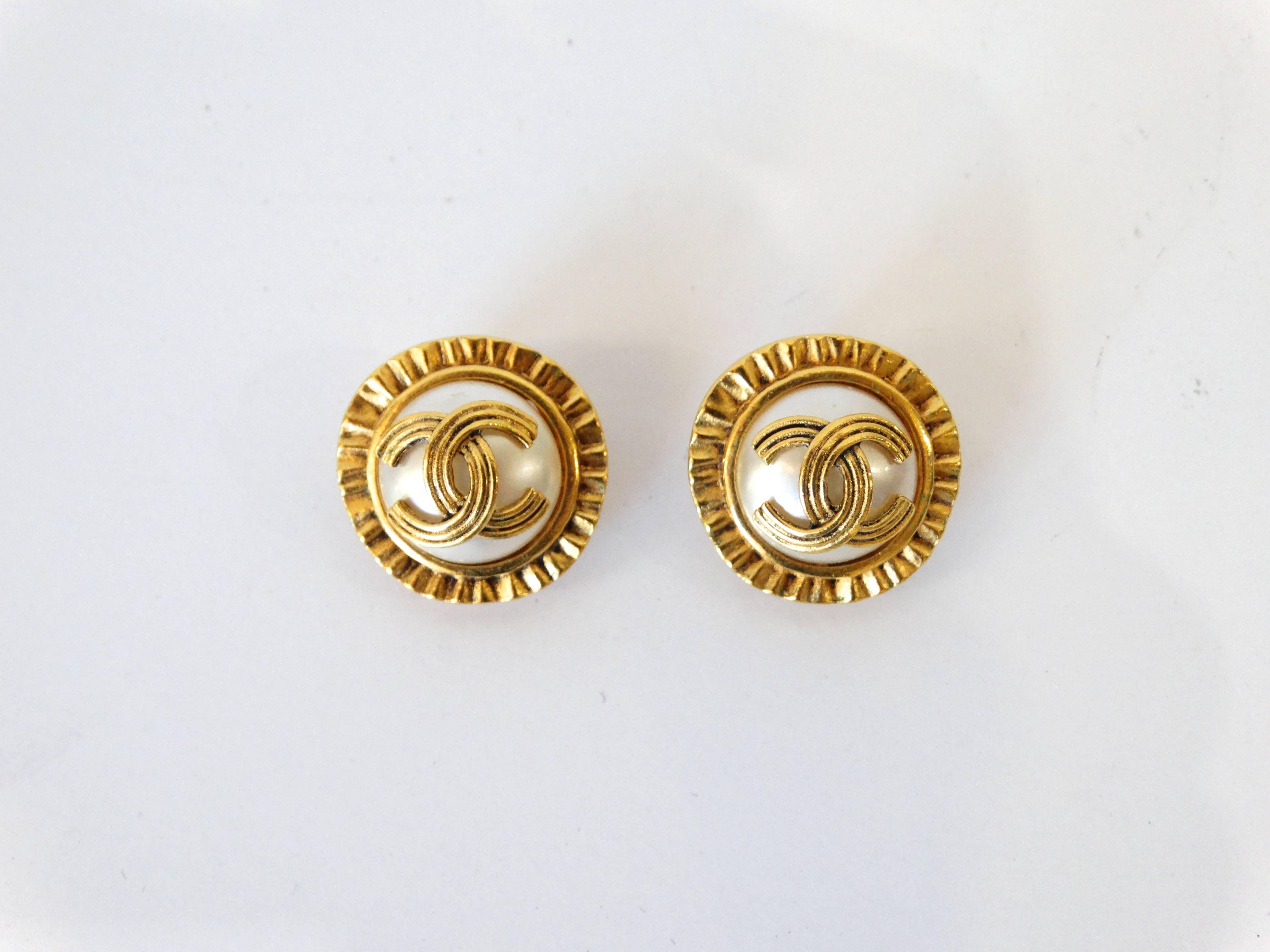 Make a statement in our 1980s earrings from iconic label Chanel! Oversized faux pearls with gold CC logo emblem over top. Trimmed with matching brilliant gold metal edges. Clip on backs. Chanel signed placard on the backs of the earrings. 

About 1”