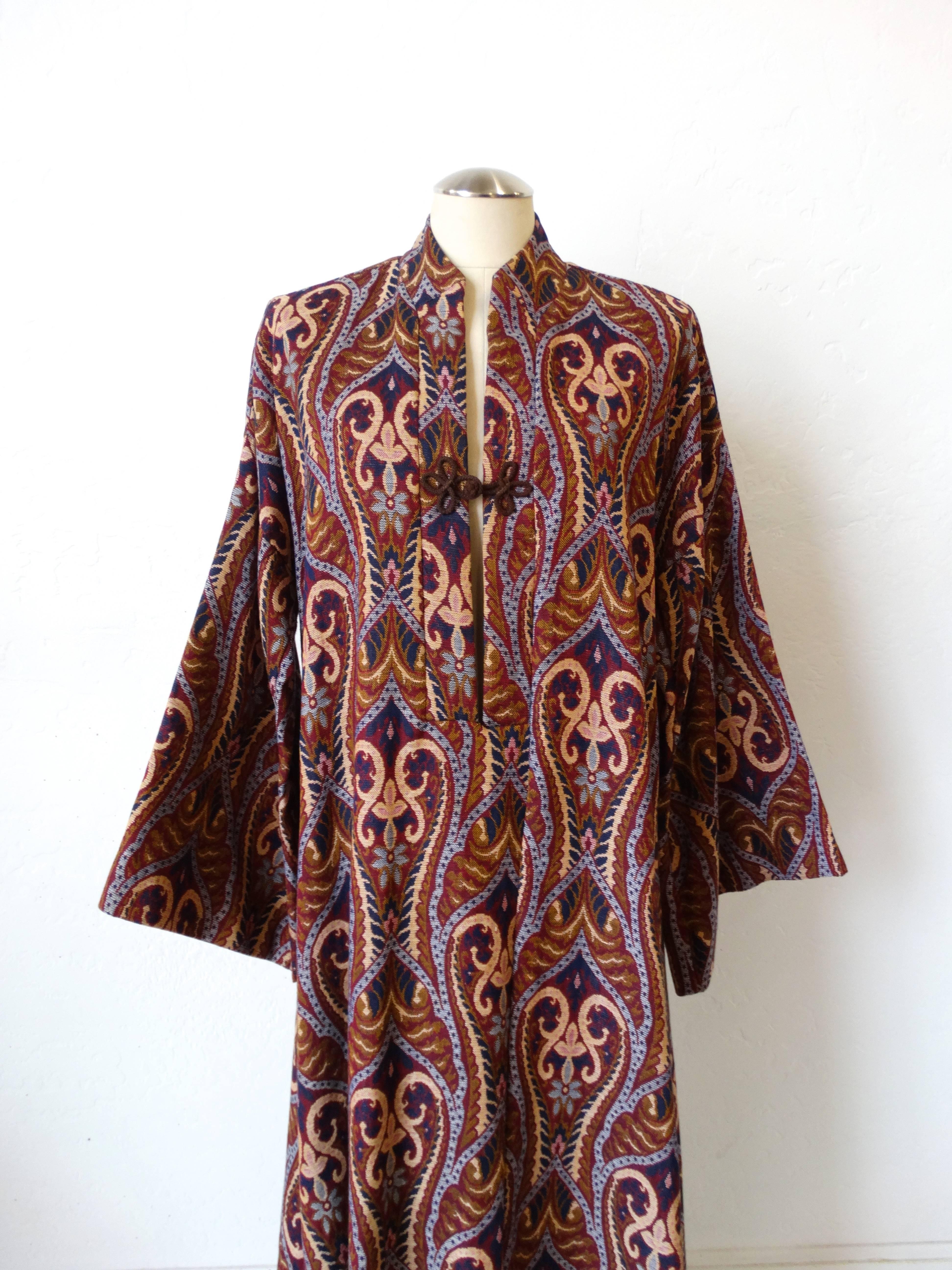 Look like a 1970s goddess in our incredible Sokolow of Beverly Hills kaftan gown! Ornate tapestry all over pattern. High neckline with a slight slit up the front, fastens with knotted rope tie at the bust. Angel wing-esque bell sleeves and maxi