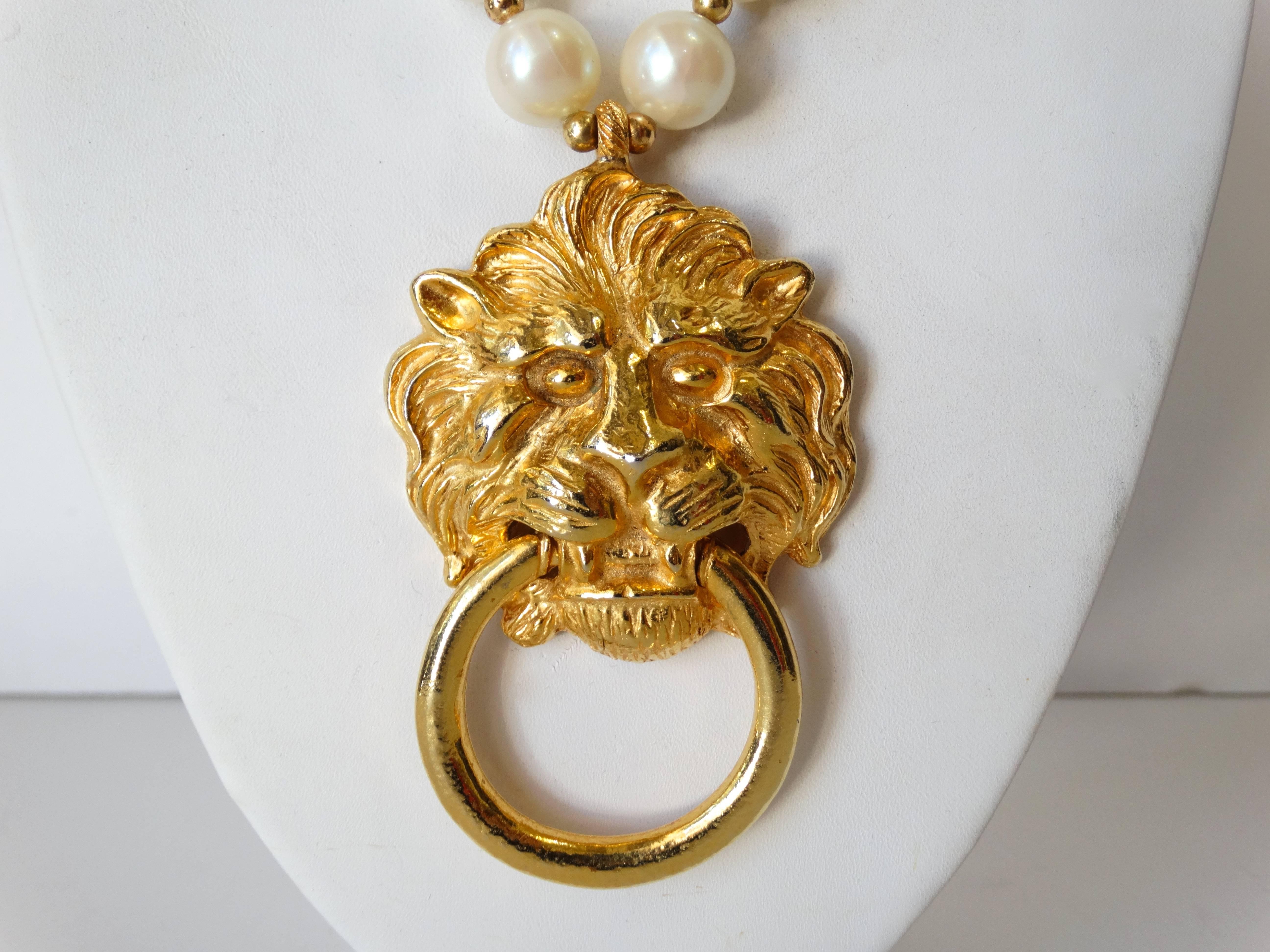 Add some fierceness to your look with our 1980s lion head necklace! Oversized faux pearl beads with large lion's head pendant. Door knocker style pendant made of brilliant gold metal. Face of a lion with hoop suspended from it's teeth. Unsigned,