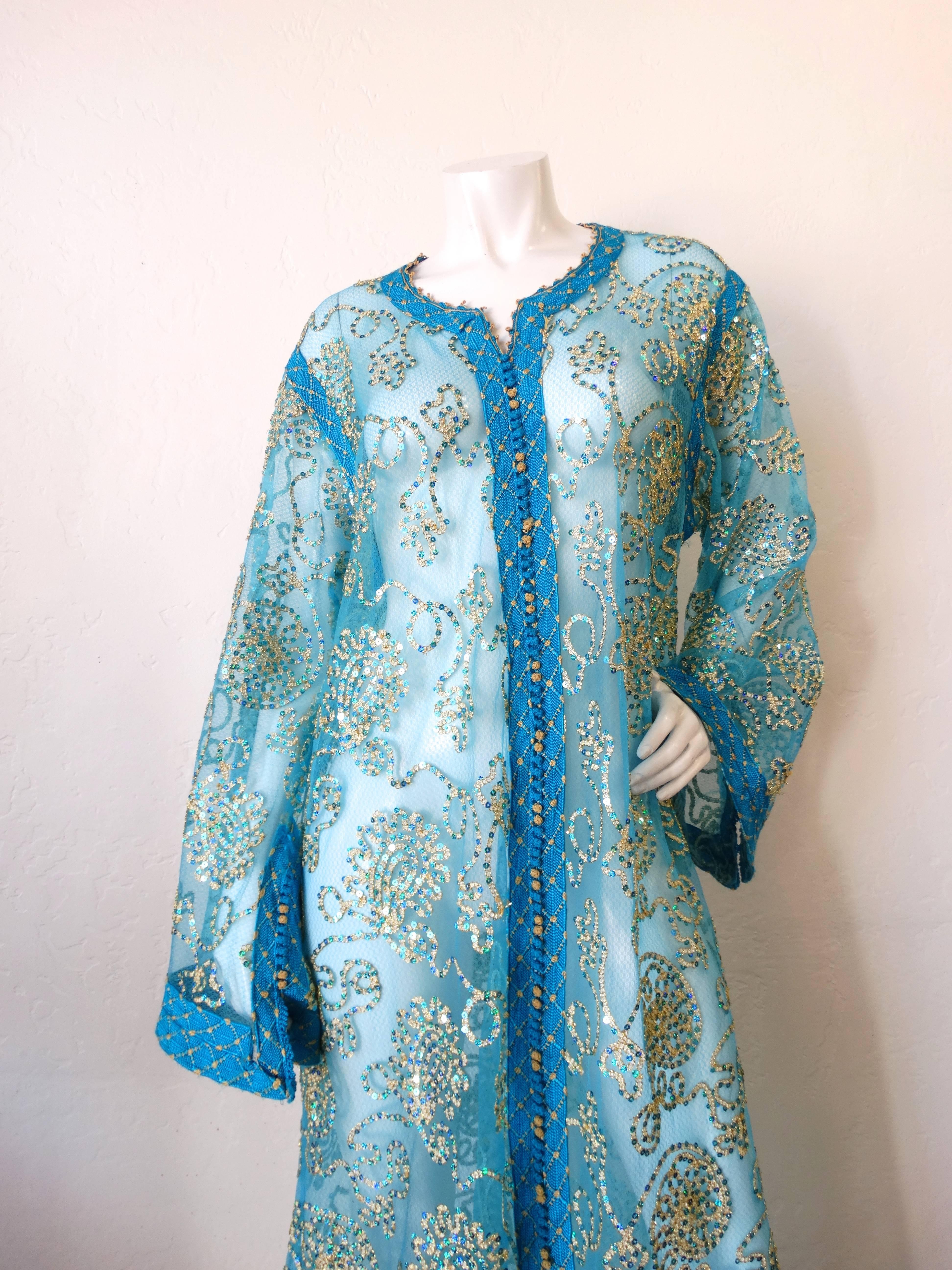Up your kaftan game with our incredible 1970s sheer blue beauty! Constructed of a fine super sheer blue fabric and accented with individual swirling lines of gold and blue sequin trim. Trimmed at the bust, cuffs and hem with blue and gold woven