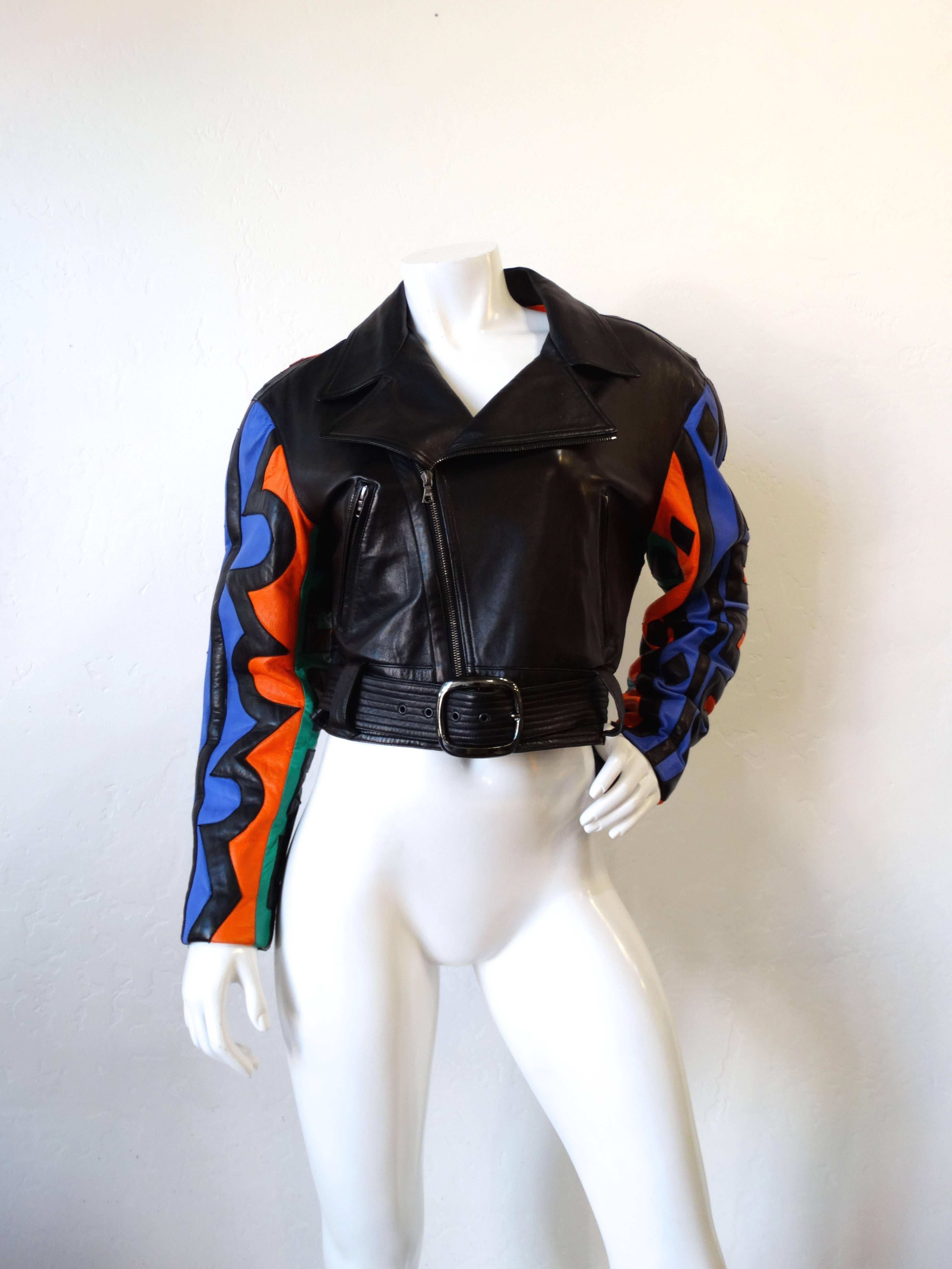 The spirit of the 1990s is alive and well in this incredible Michael Hoban jacket! Solid black leather bodice with super colorful sleeves and back. Tribal print patchwork in shades of teal, blue black and orange. Classic motorcycle jacket